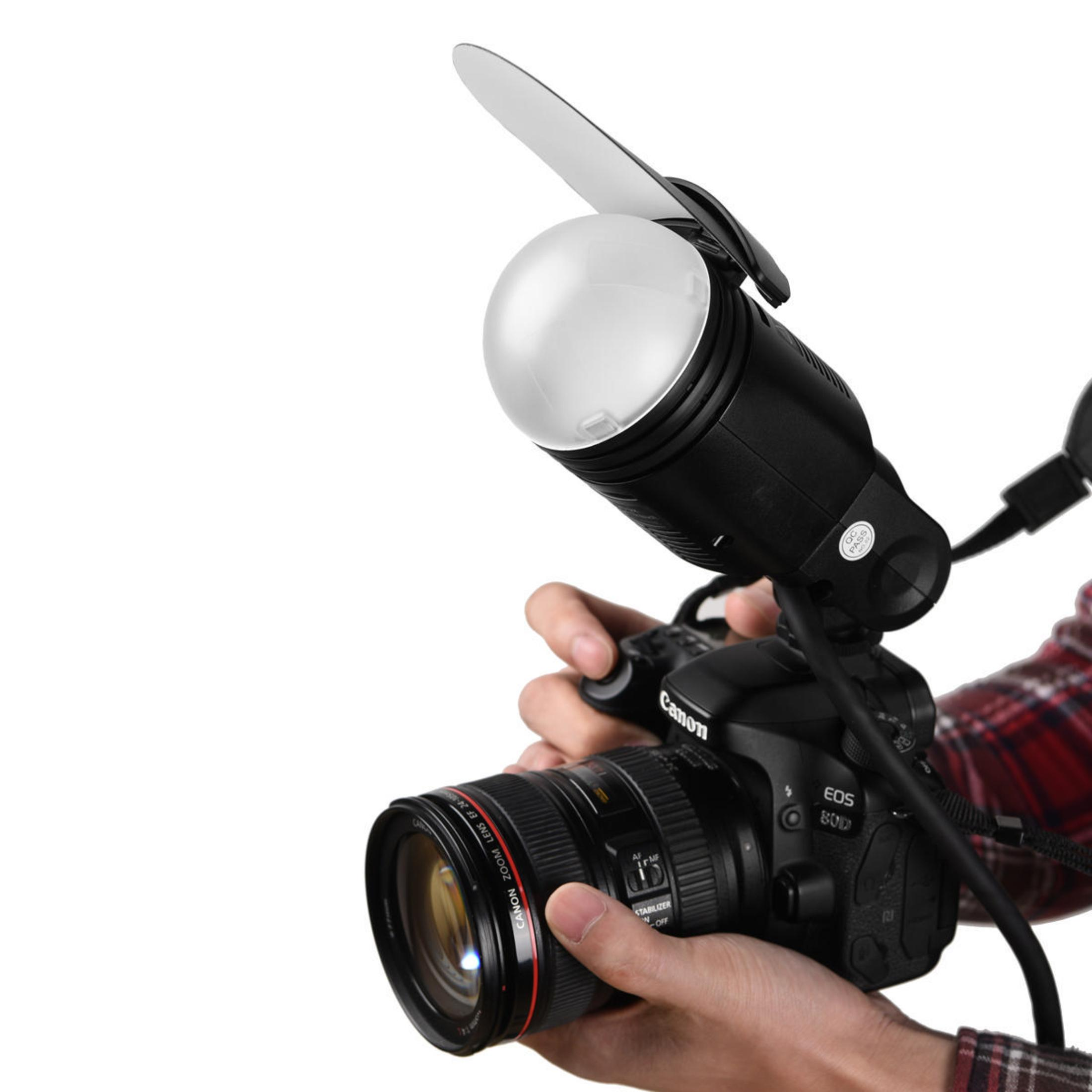Ein Fotograf hält eine Canon-Kamera mit Blitz, bereit für ein Fotoshooting, vor weißem Hintergrund.