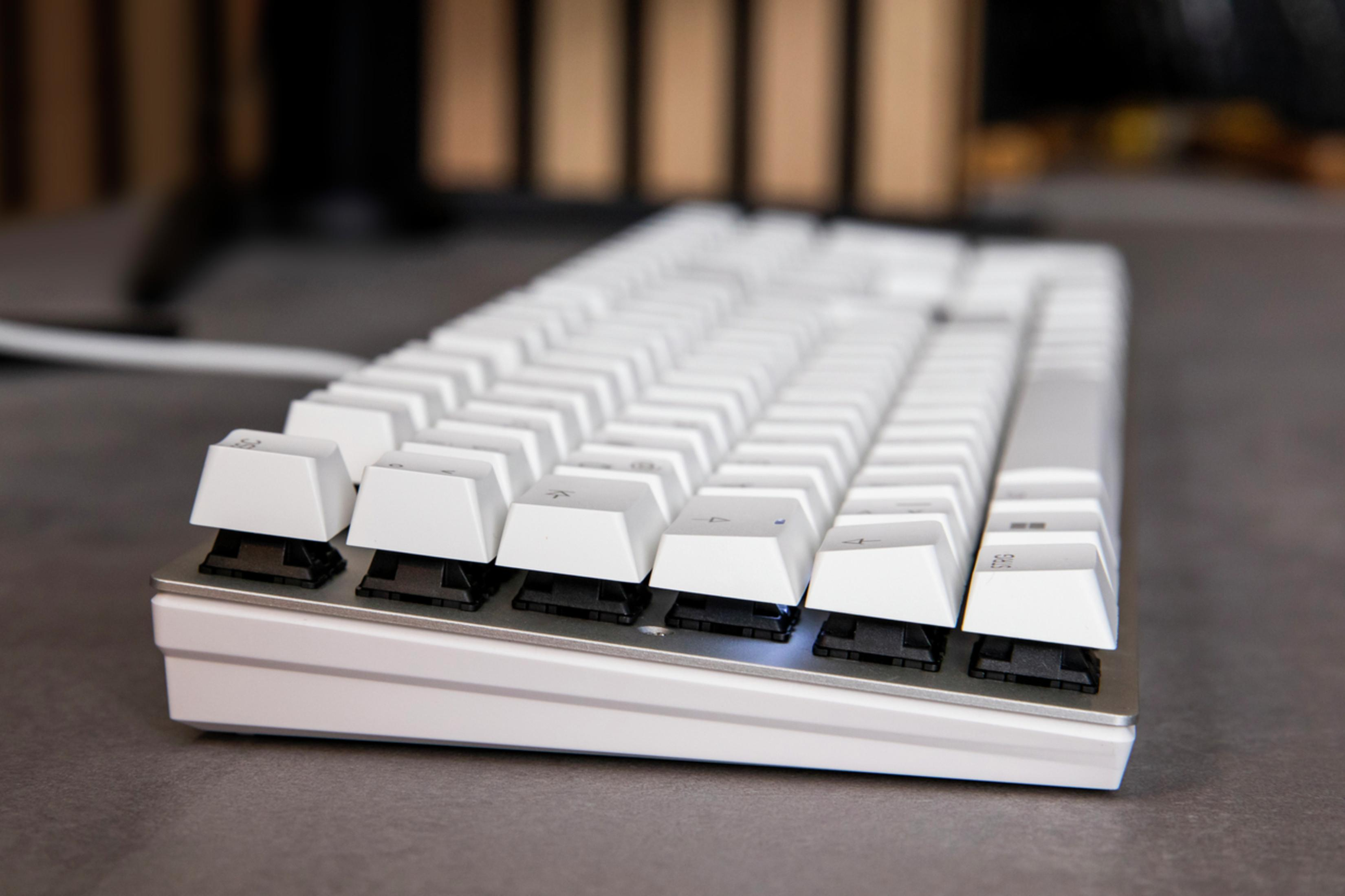 Eine weiße mechanische Tastatur mit weißen Tastenkappen auf grauer Oberfläche.
