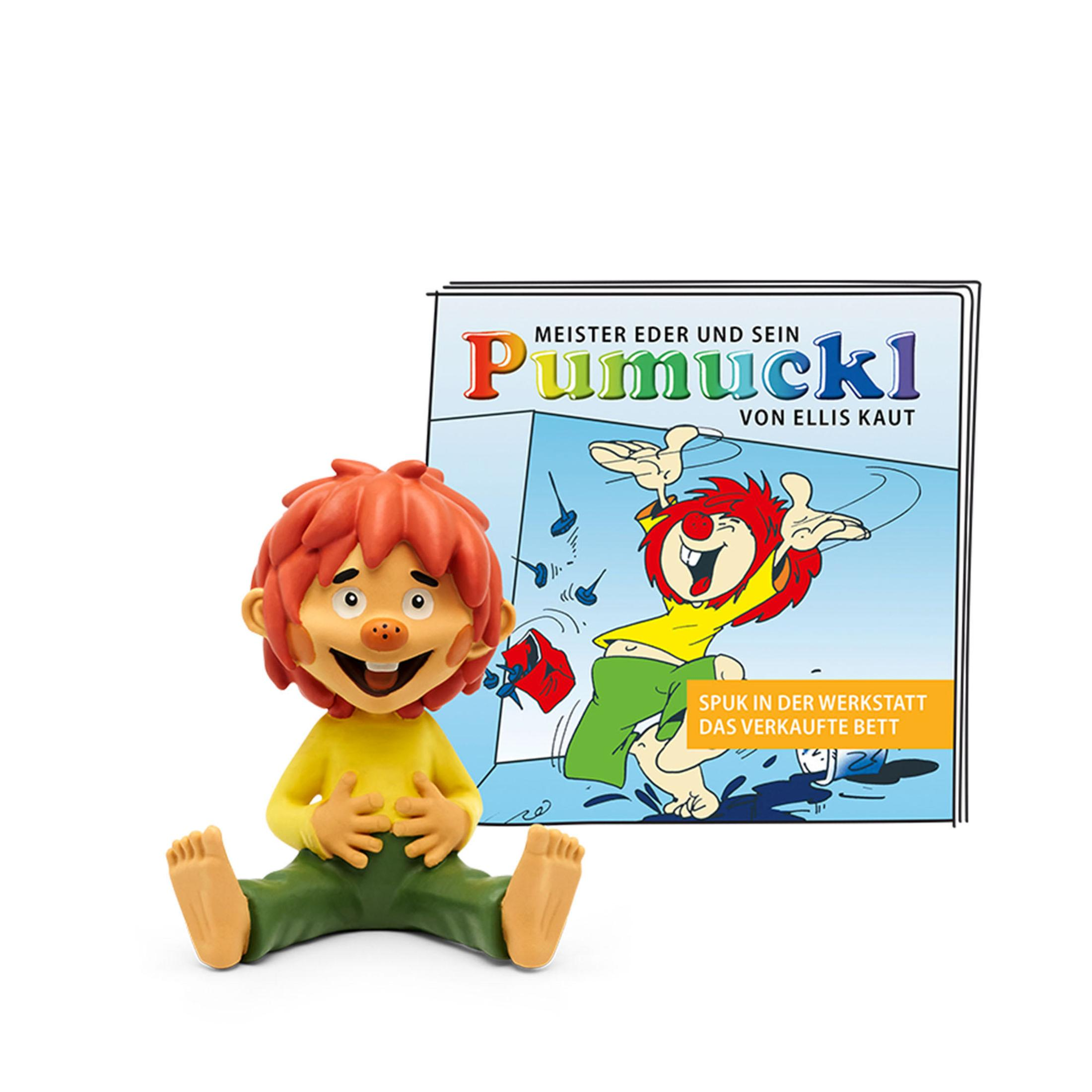 Pumuckl-Figur sitzt mit einem Buch hinter sich. Das Buchcover zeigt eine Zeichnung von Pumuckl.
