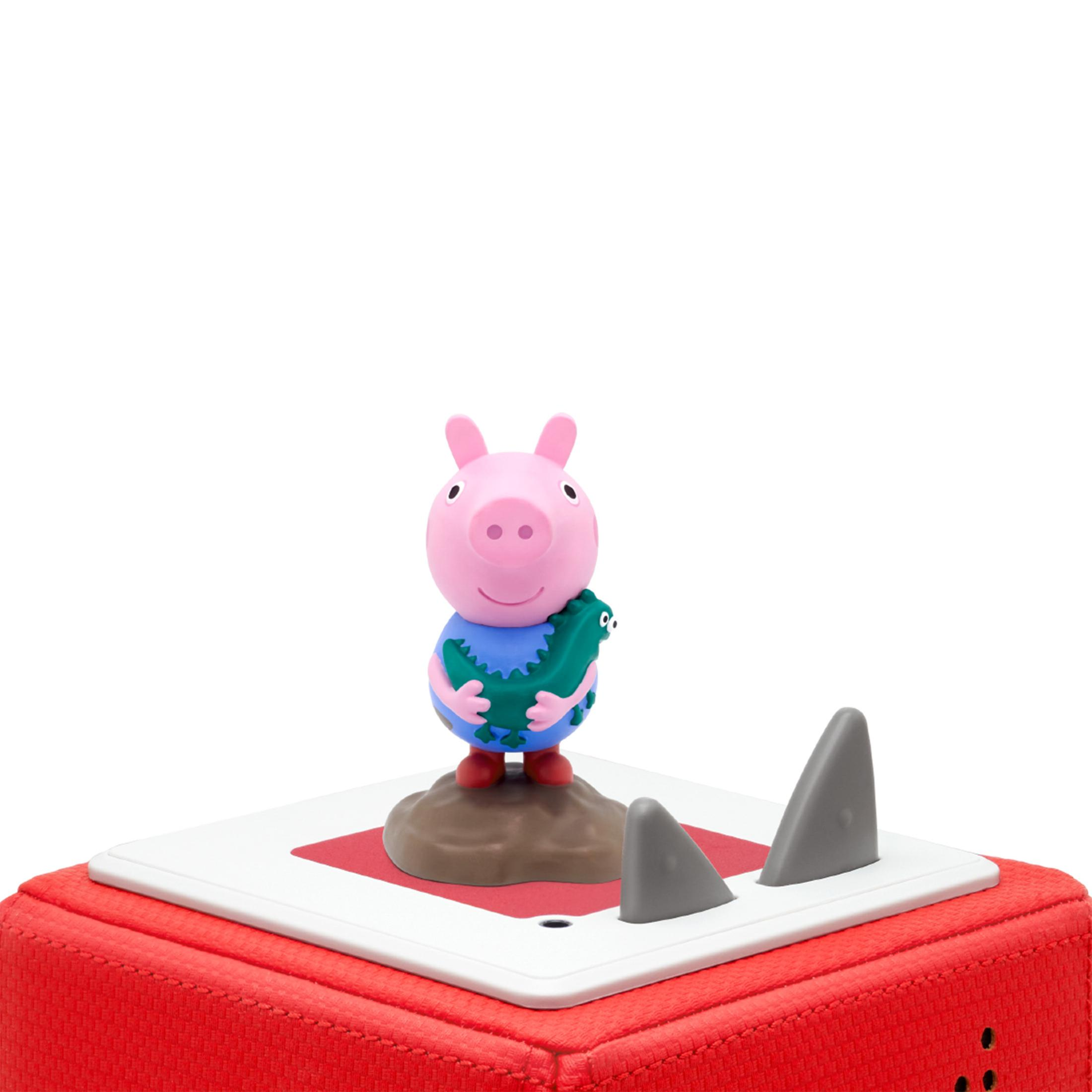 Peppa Wutz Spielfigur, die ein Spielzeug-Dinosaurier hält. Auf roter Basis mit zwei grauen Haiflossen. Weißer Hintergrund.