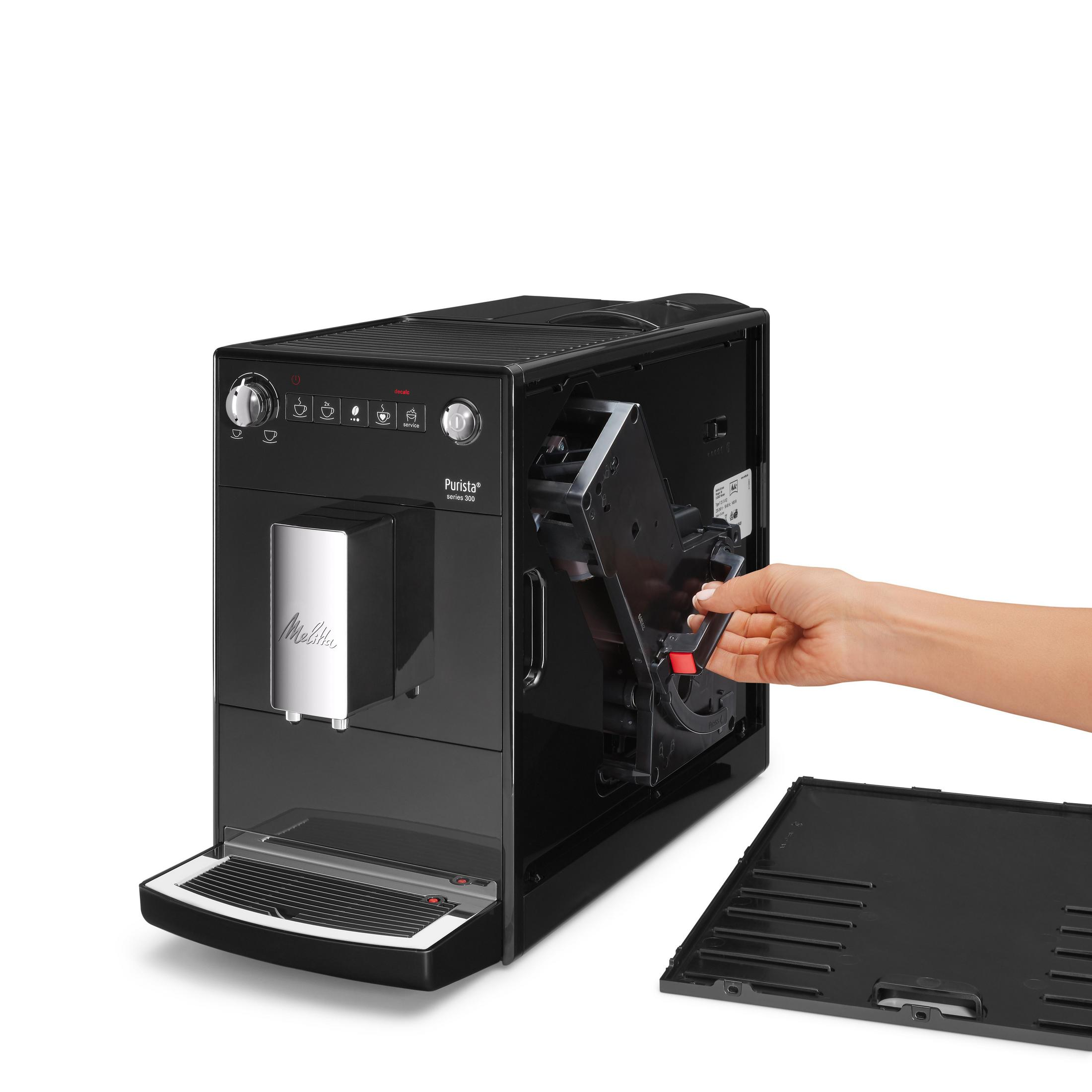 Osoba demontująca czarny ekspres do kawy. Widoczne są różne elementy i wyjmowana taca.