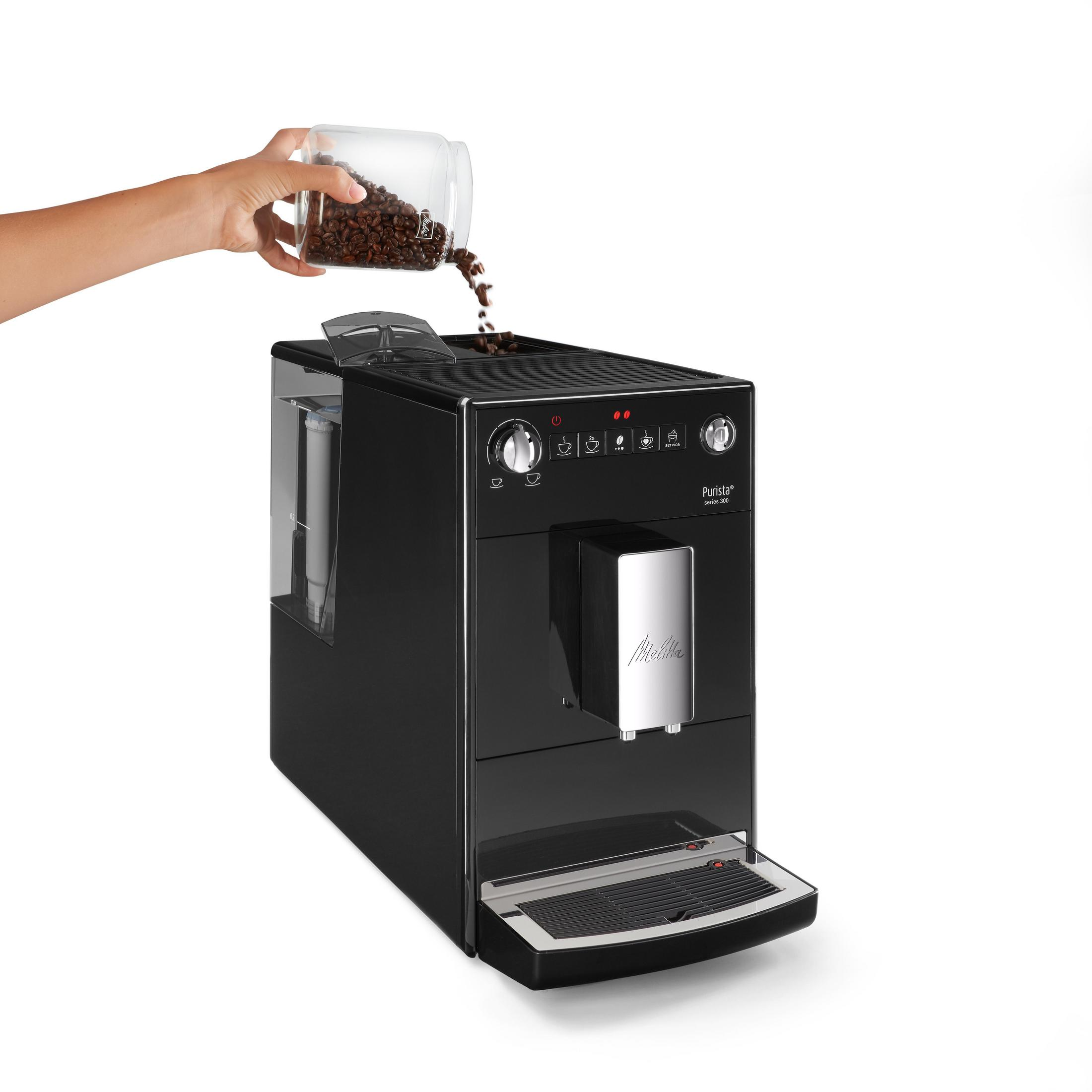 Osoba wsypująca ziarna kawy do czarnego ekspresu do kawy.