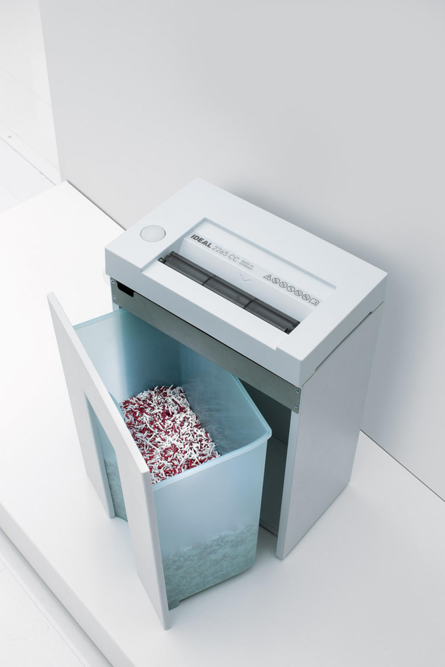 Ein weißer Aktenvernichter mit einem Behälter voller geschreddertem Papier auf einer weißen Oberfläche.