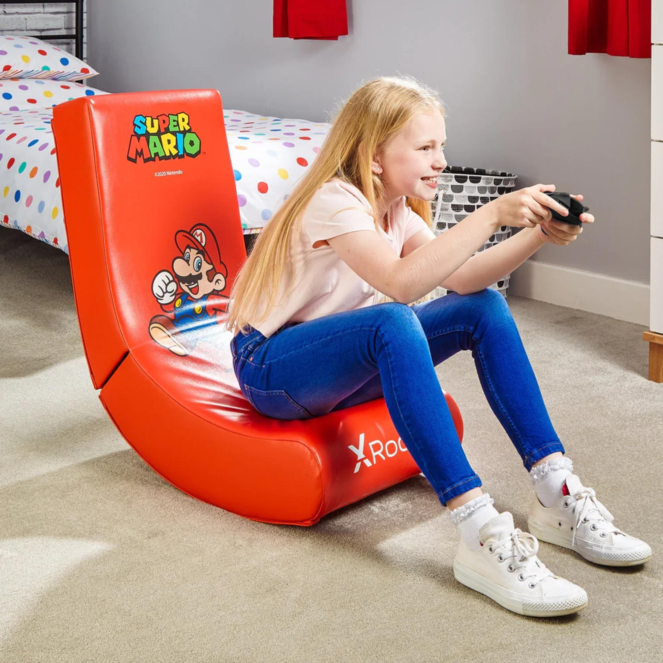 Junges Mädchen spielt ein Spiel auf einem roten Super Mario Schaukelstuhl.