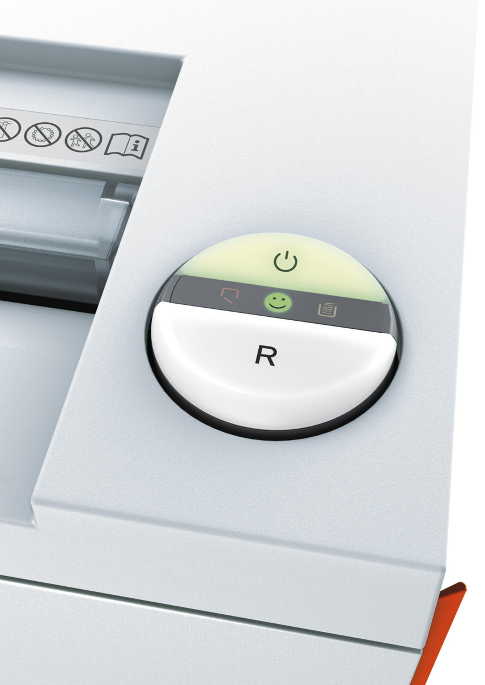Nahaufnahme des Einschaltknopfes einer weißen Maschine. Grün beleuchtetes Smiley-Gesicht und R unten.