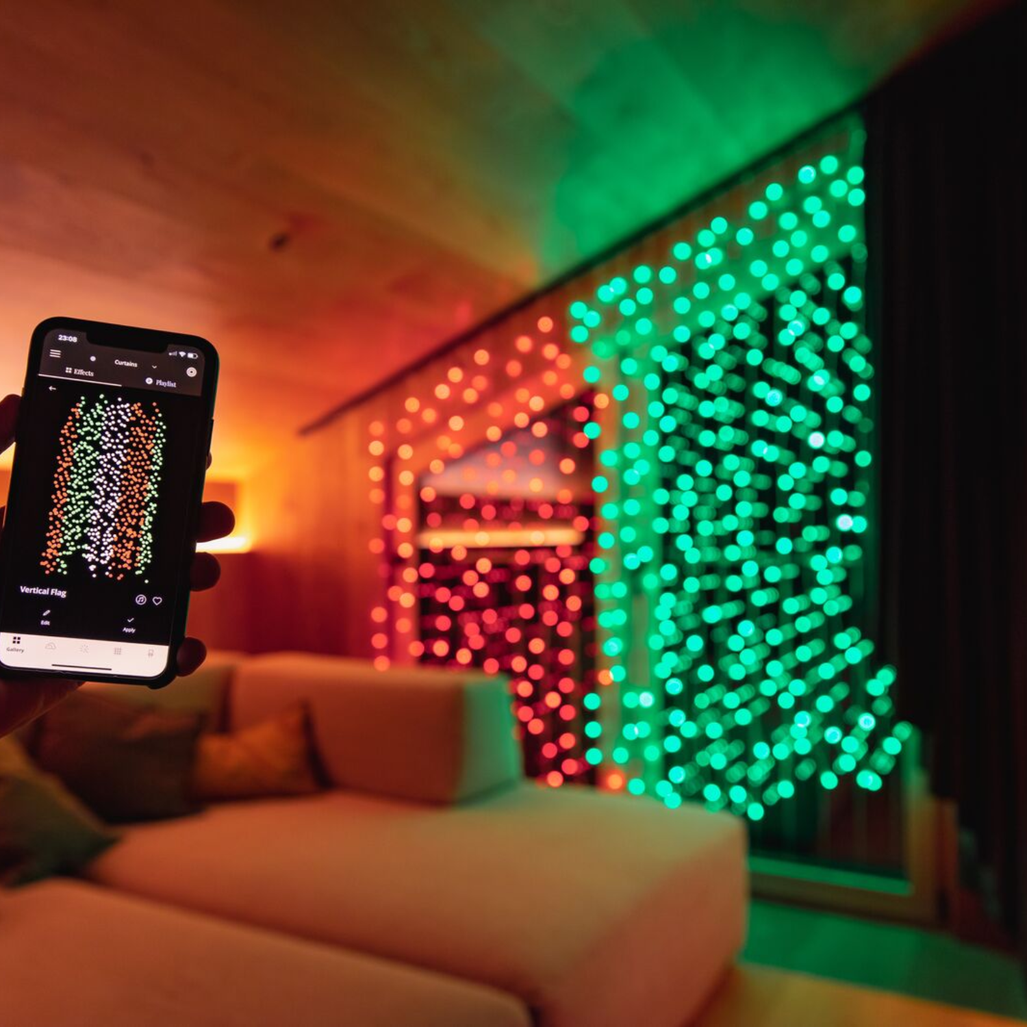 Osoba trzymająca telefon z wzorem światełek świątecznych, z czerwonymi i zielonymi światłami na ścianie.