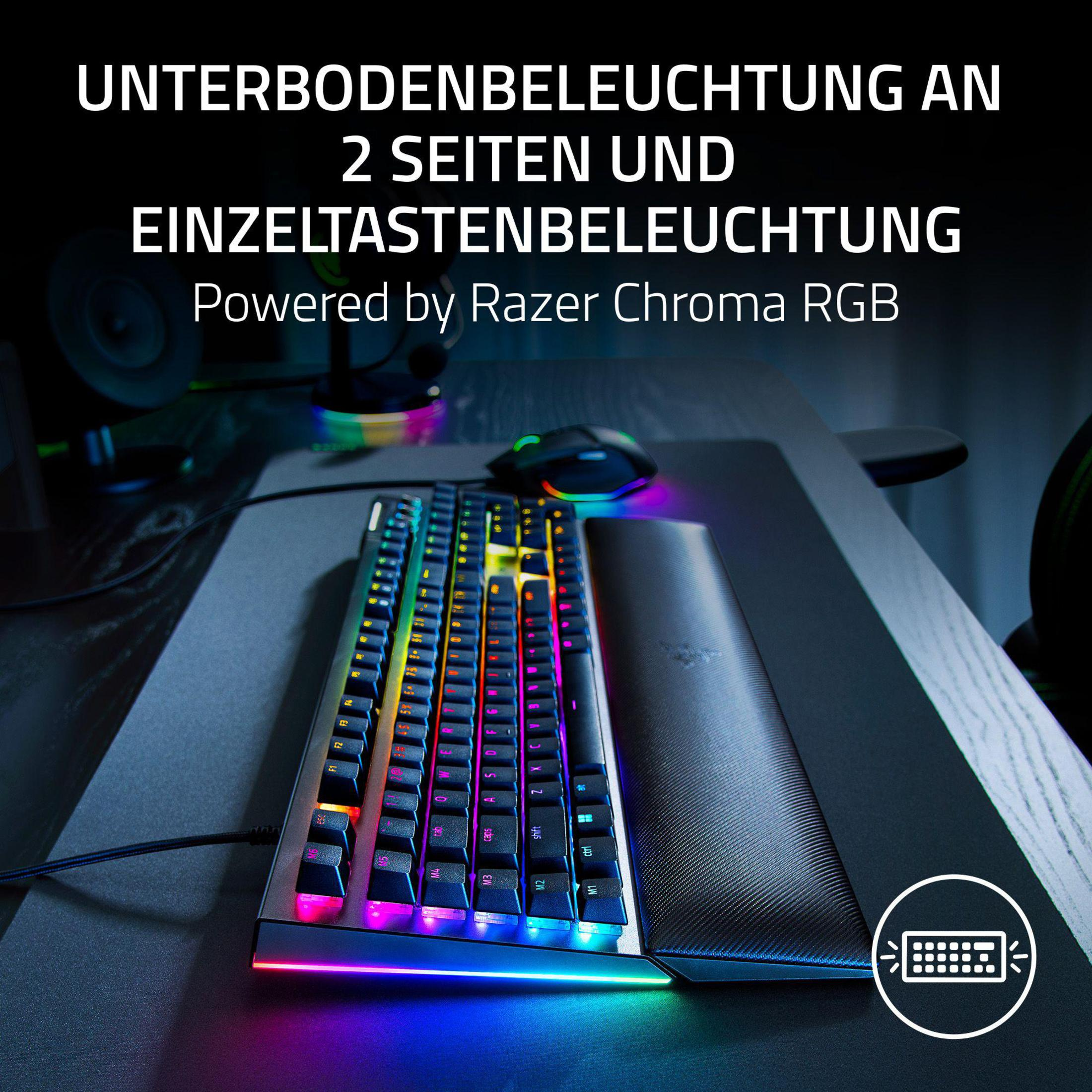 Eine beleuchtete Gaming-Tastatur auf einem Schreibtisch mit Maus und Handgelenkstütze.