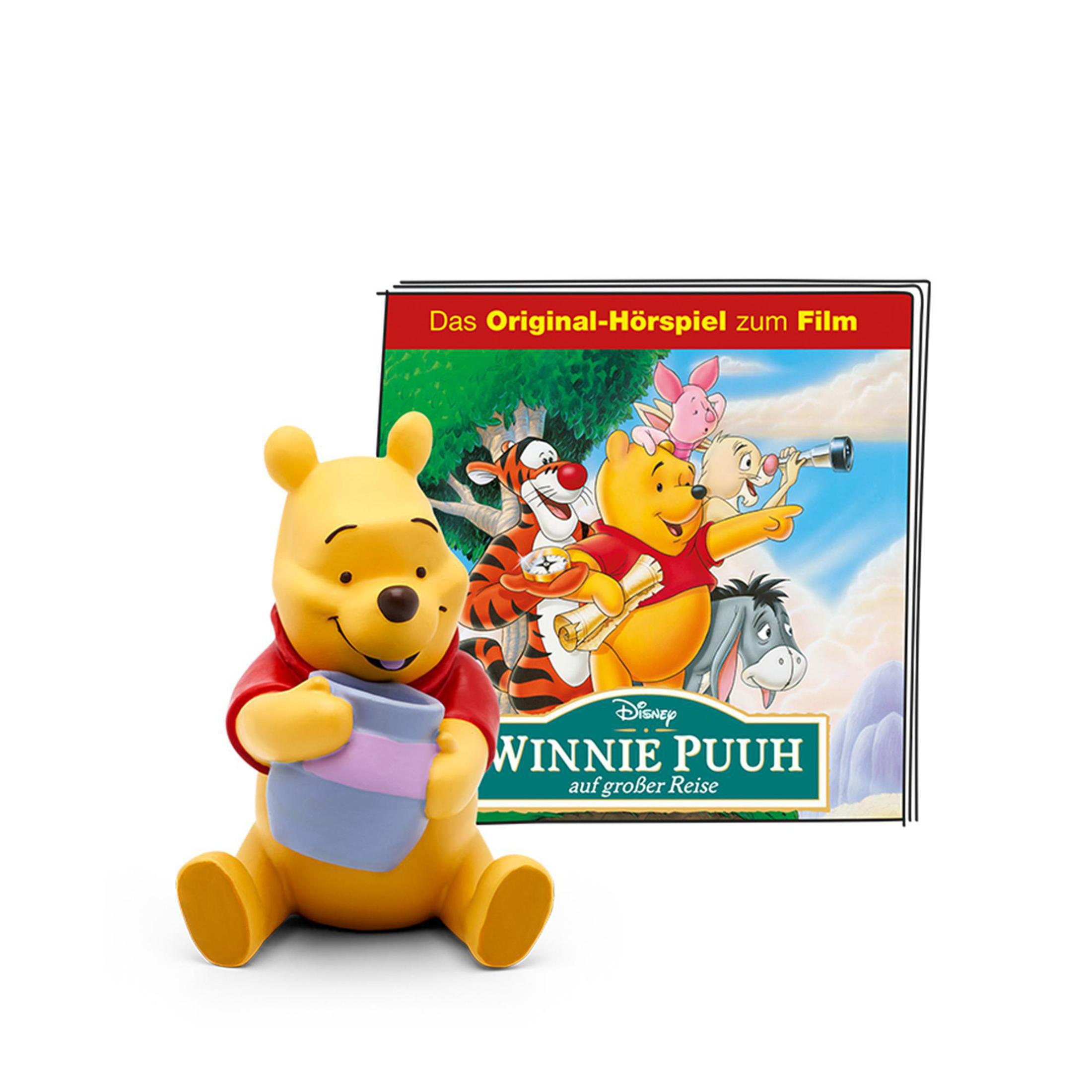 Winnie Puuh Figur sitzt vor einem Buchcover mit Zeichentrickfiguren.