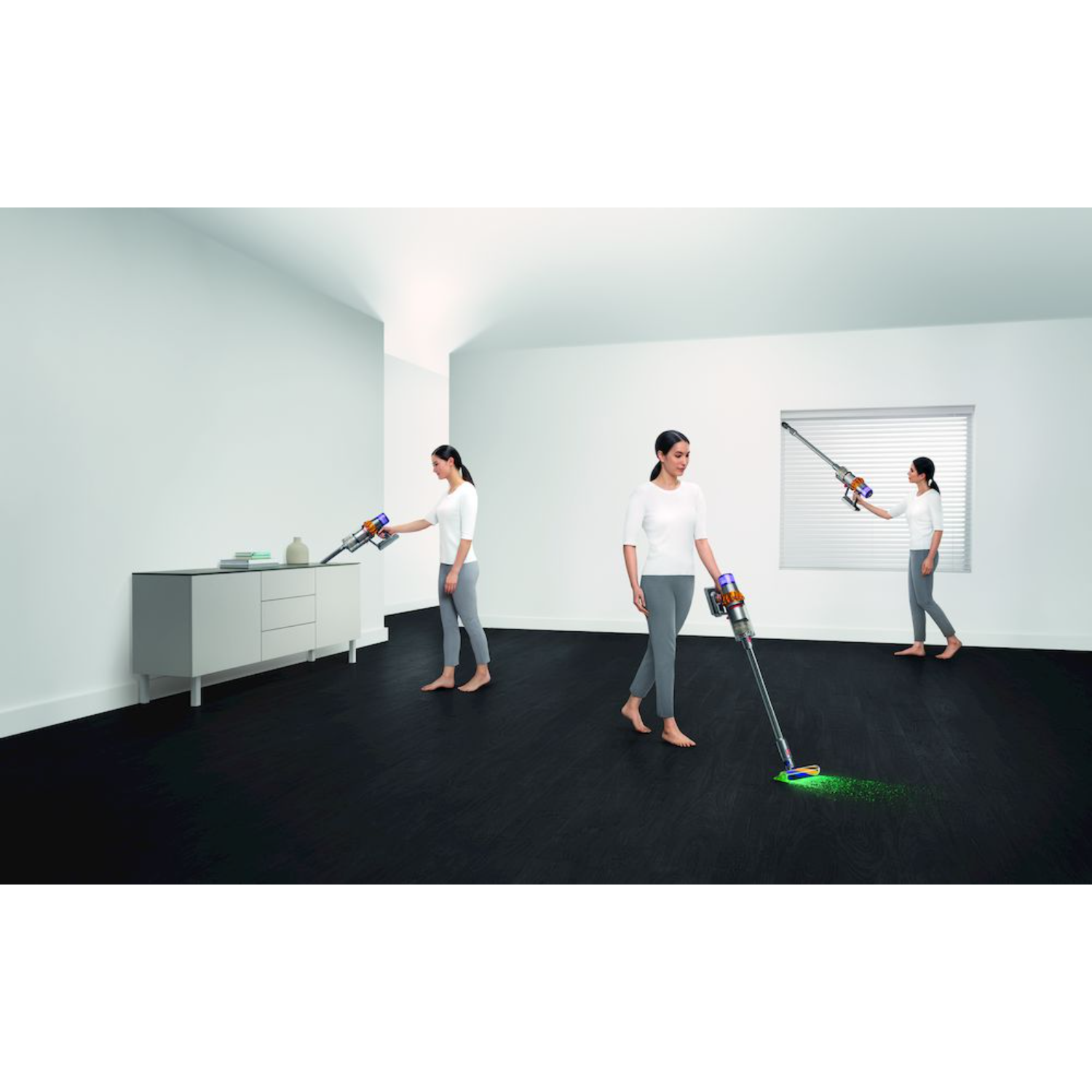 Trzy kobiety odkurzają pokój odkurzaczem Dyson. Jedna odkurza stół, druga podłogę, a trzecia patrzy.