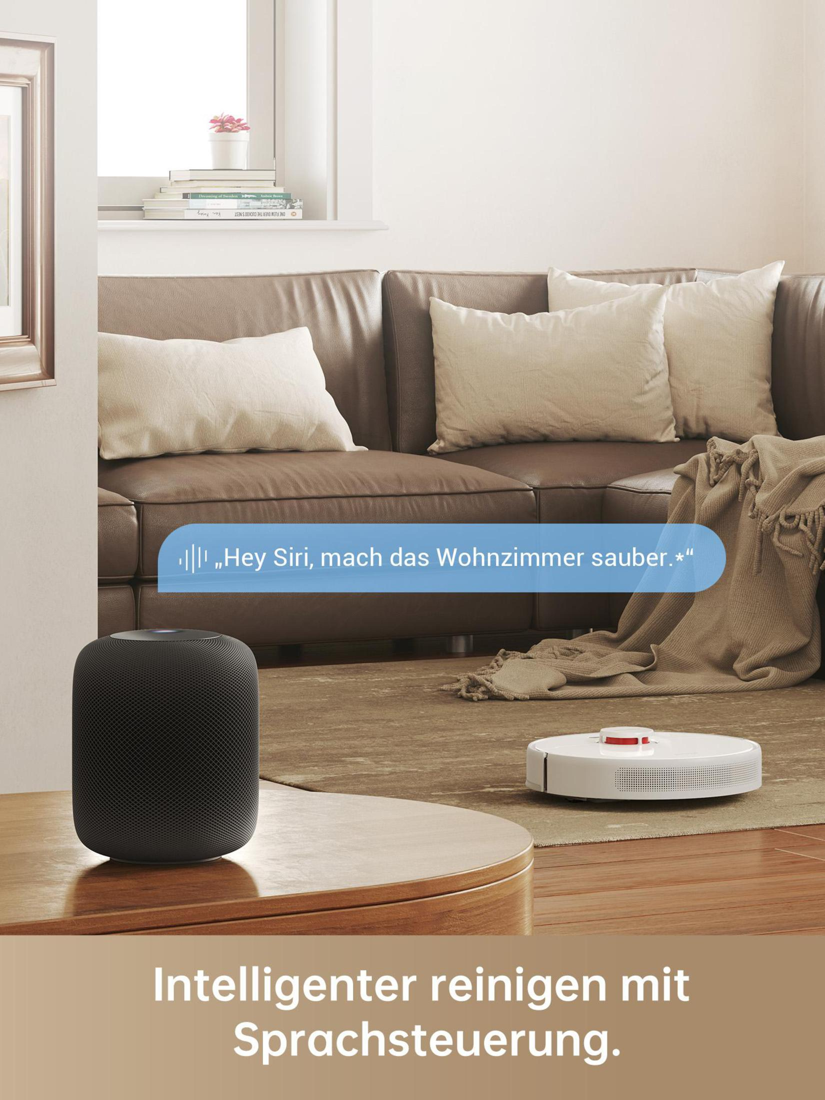 Salon z brązową skórzaną sofą, odkurzaczem robotem i inteligentnym głośnikiem na stole.