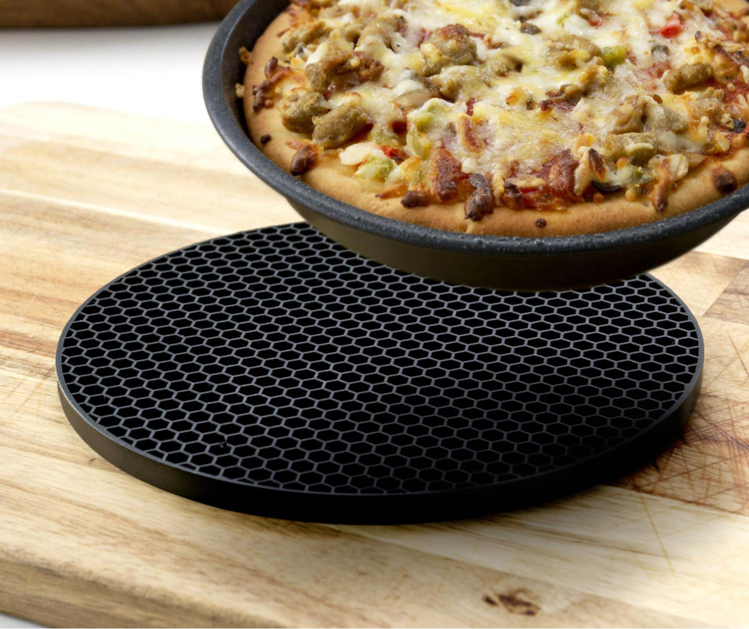 Pizza en un salvamanteles negro, sobre tabla de cortar. Pizza en sartén negra.