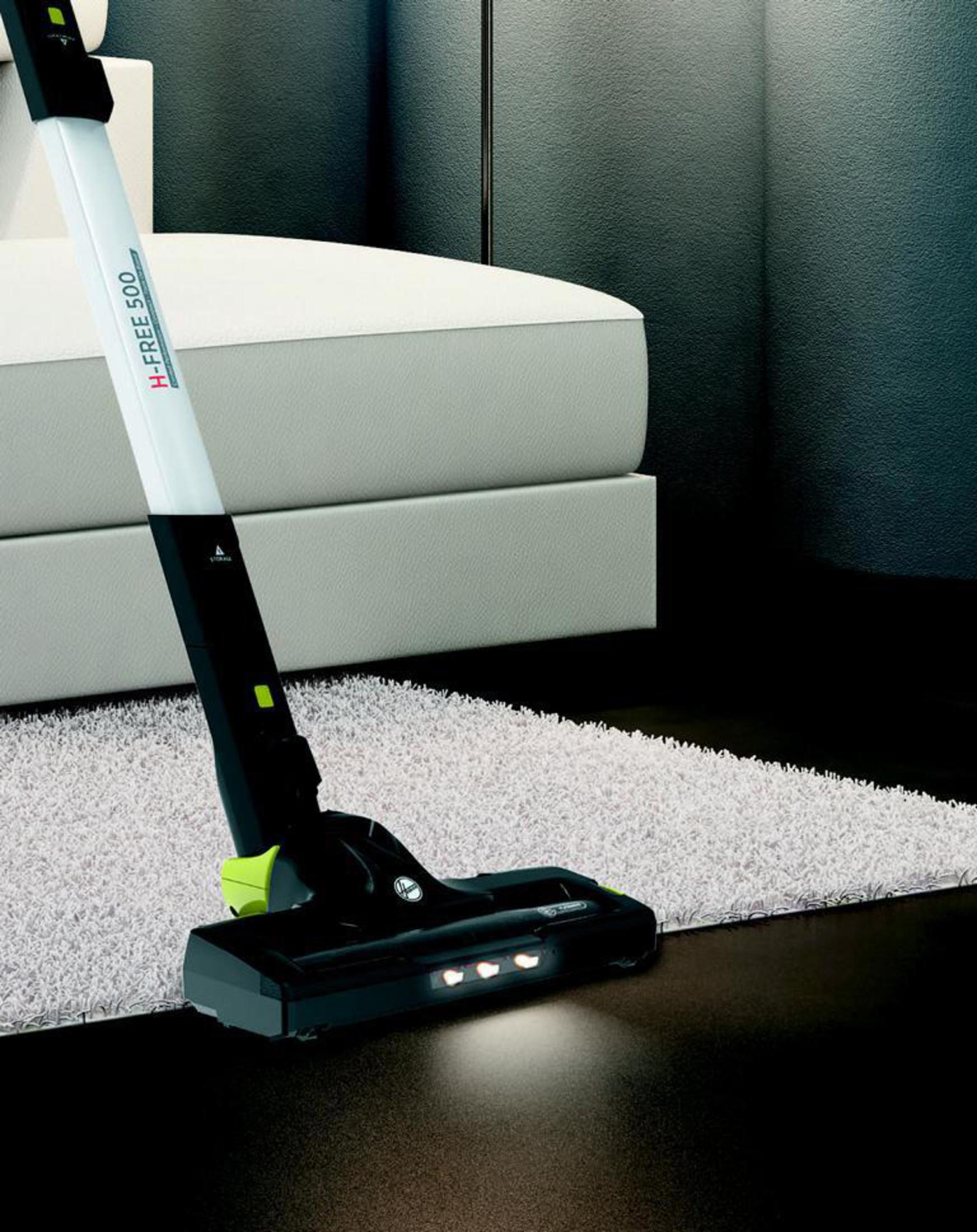 Aspiradora Hoover H-FREE 500 limpiando un piso. La aspiradora es negra y blanca con luces.