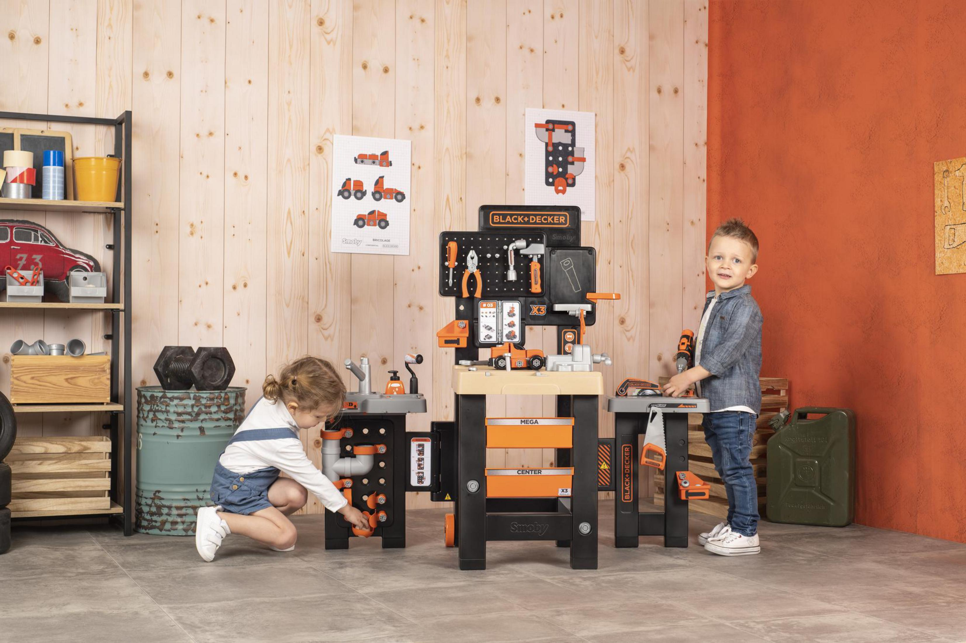 Zwei Kinder spielen mit einer Black+Decker Spielzeugwerkbank. Werkzeuge und eine Zeichnung auf der Rückseite.