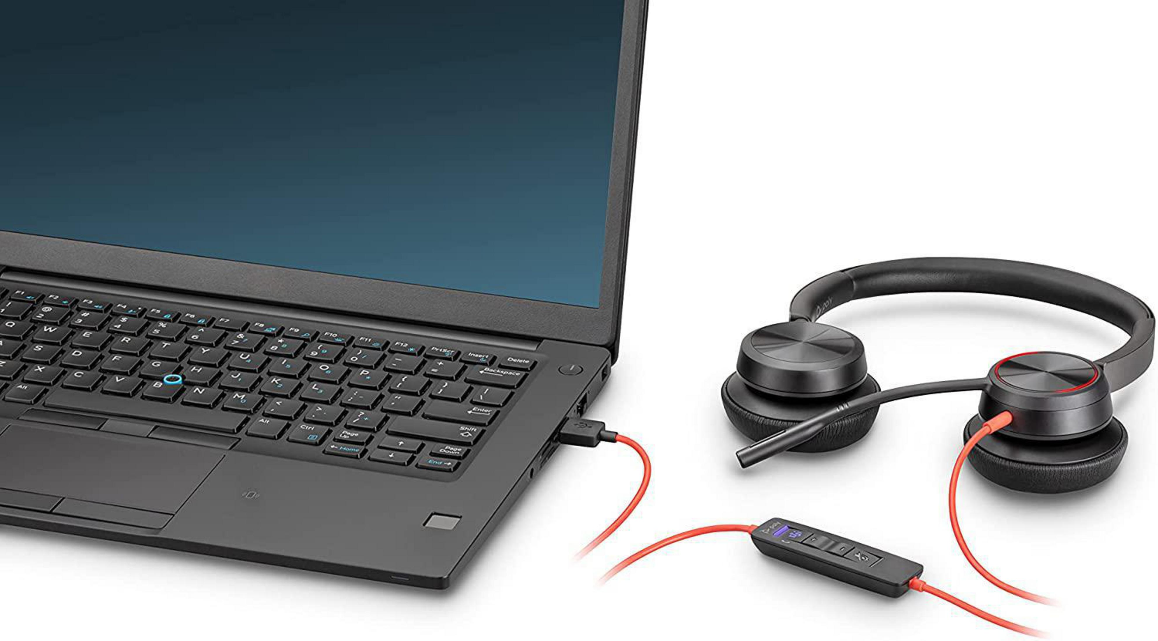 Laptop ze słuchawkami podłączonymi. Czerwony kabel je łączy. Kabel USB również jest czerwony.