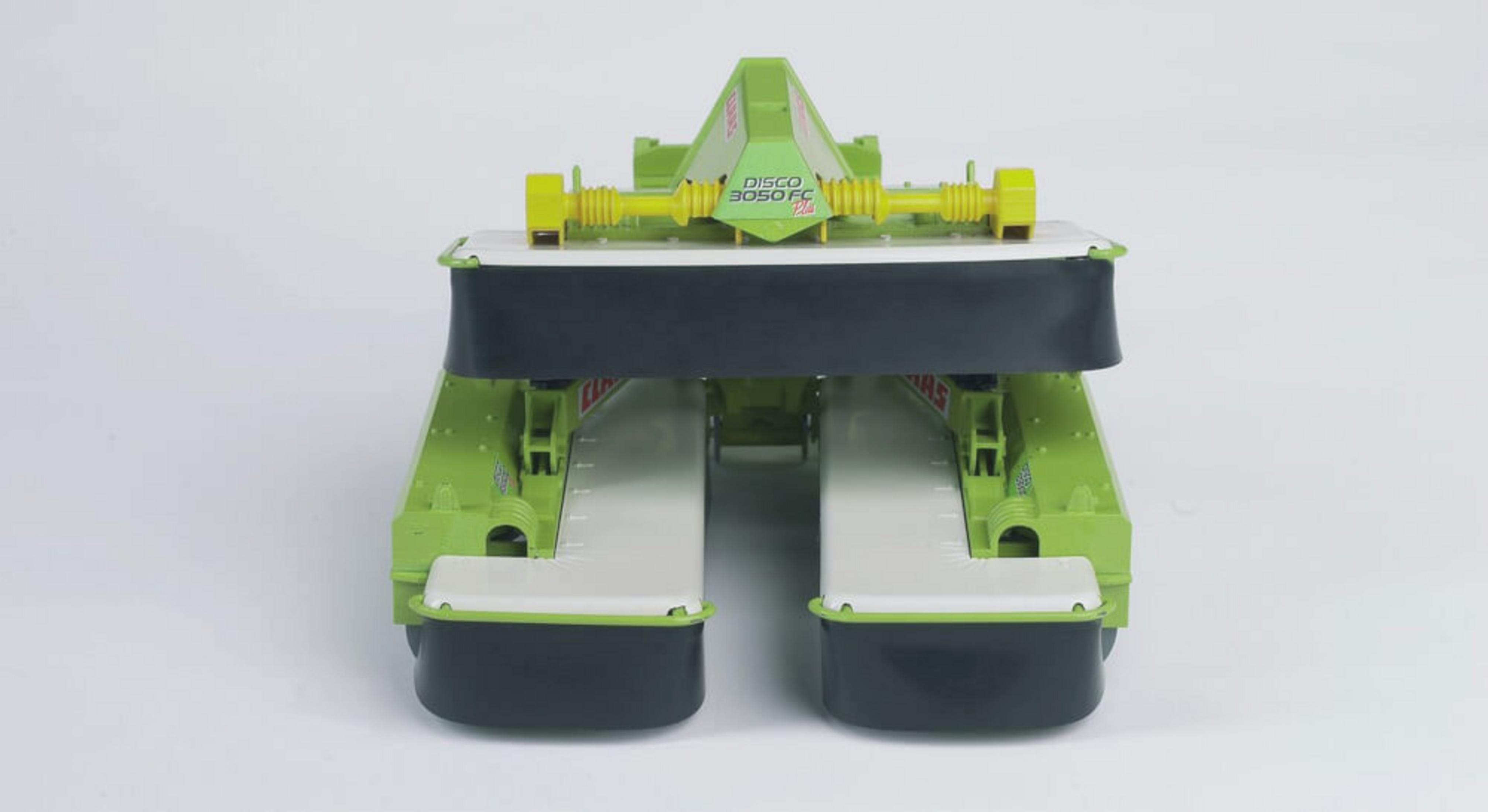 Zielona maszyna rolnicza. Koła są czarne i stoi na białej powierzchni. Tło jest białe.