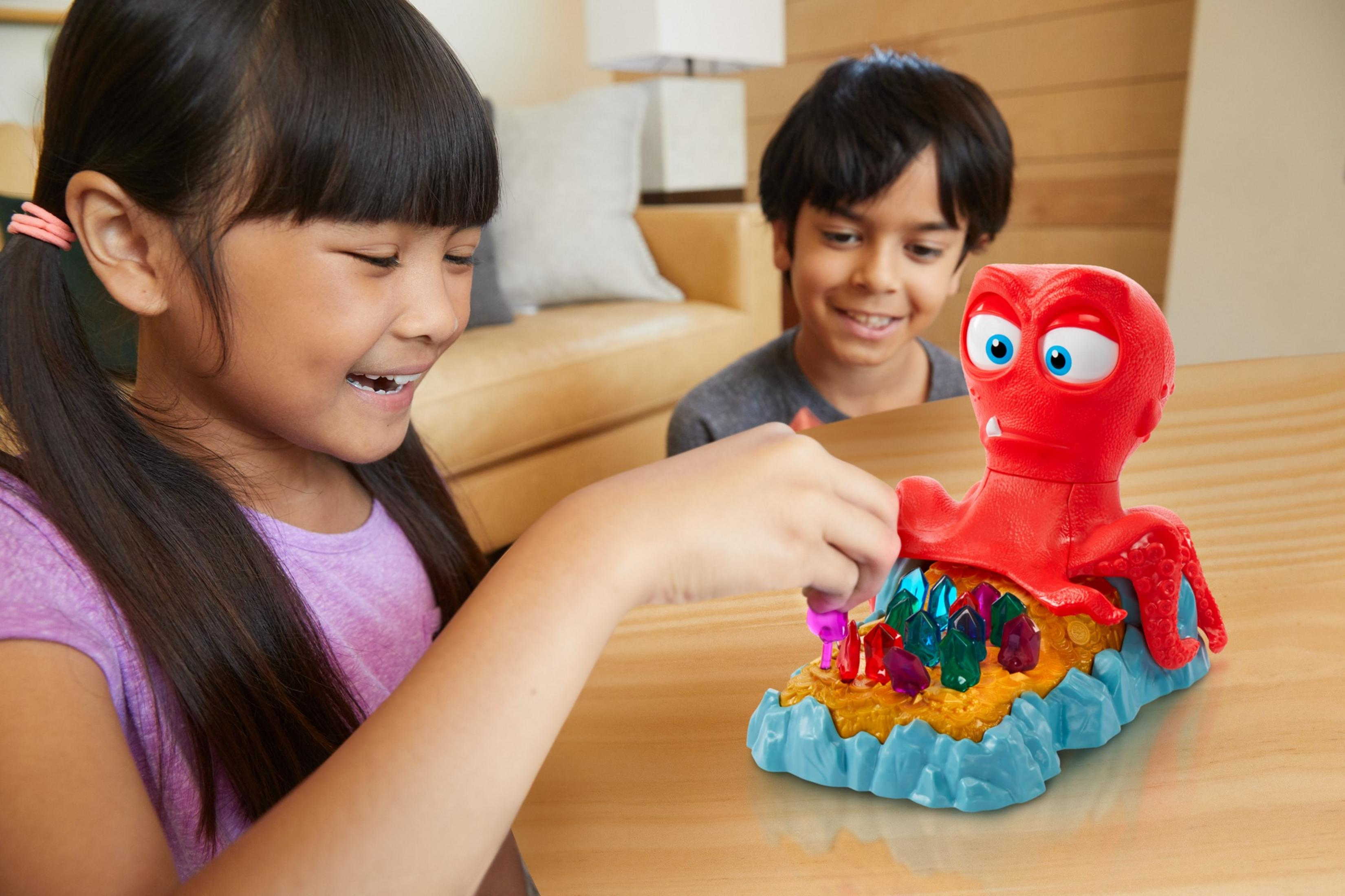 Zwei Kinder spielen ein Brettspiel mit einem roten Oktopus.