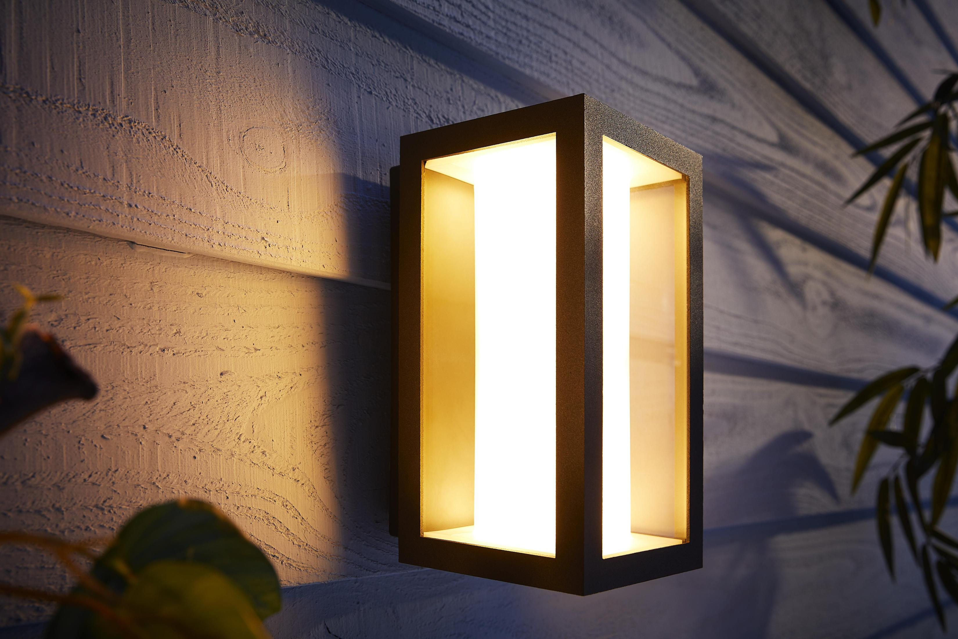 Un applique murale extérieure noire avec une lumière blanche brillante qui en émane.