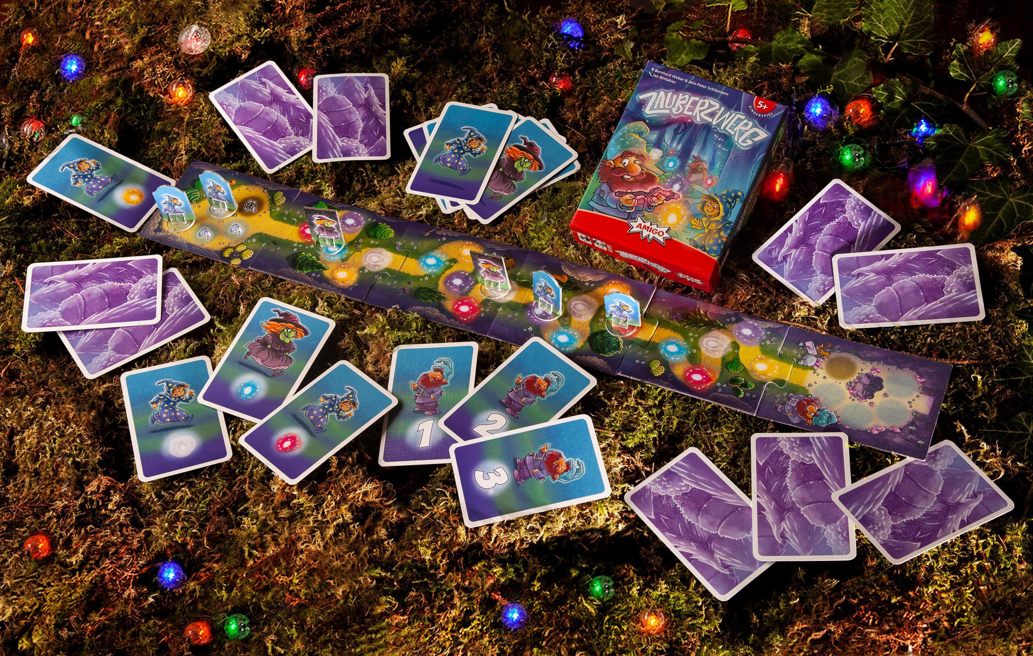 Jeu de société avec cartes, un chemin et une boîte, sur mousse avec guirlande.