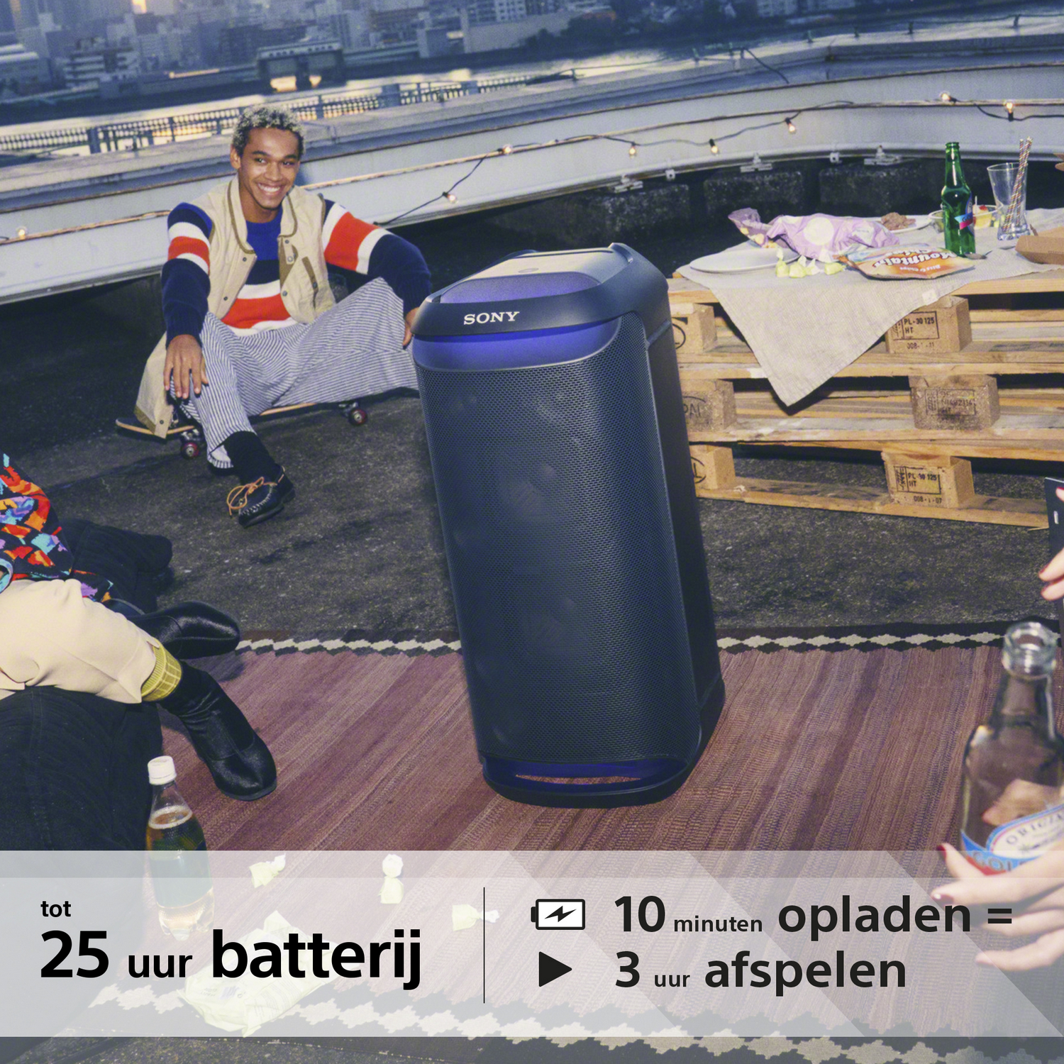 Ein tragbarer Sony-Lautsprecher auf einem Dach, mit einer Person und verschiedenen Gegenständen. Text: 25 Stunden Akku.