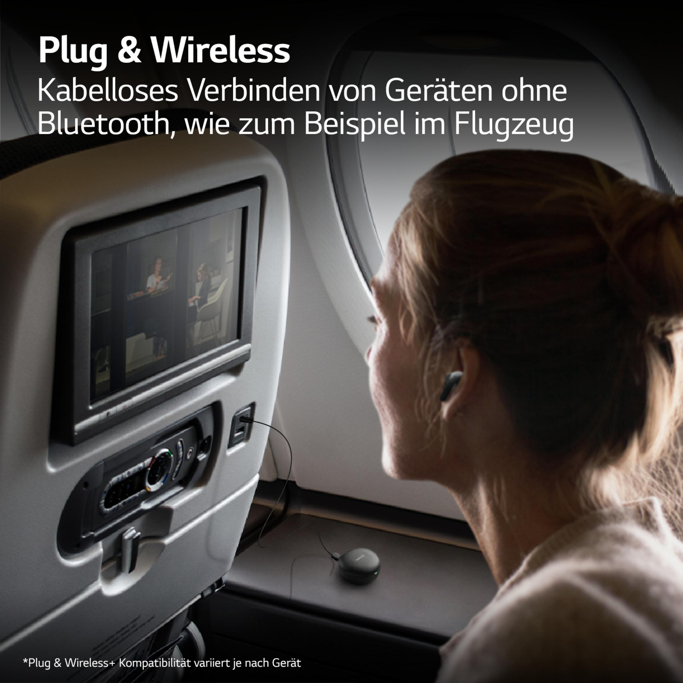 Eine Frau im Flugzeug benutzt kabellose Ohrhörer, vor ihr ein Bildschirm mit einem Video.