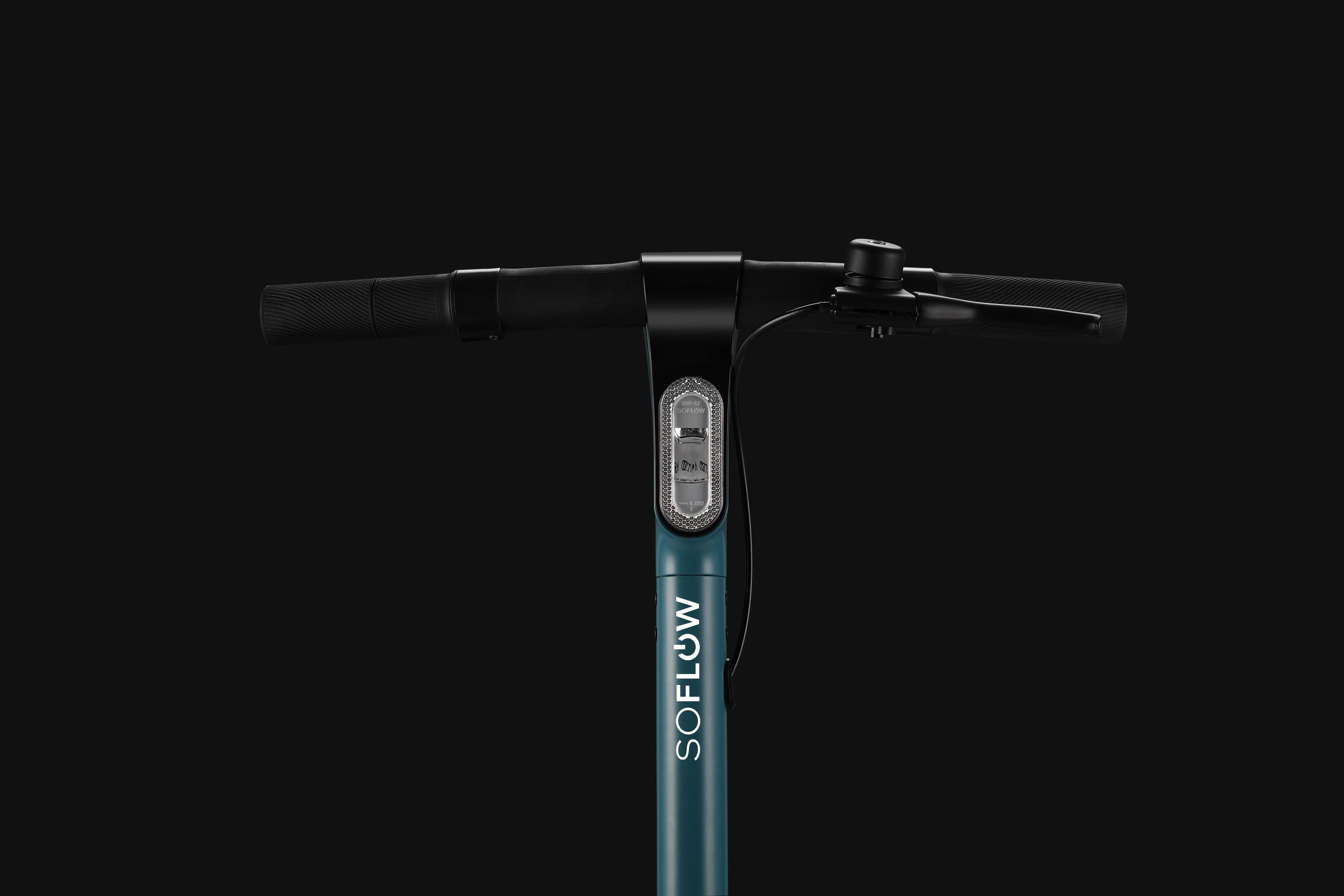 Primo piano del manubrio nero di uno scooter, con un logo blu e bianco.