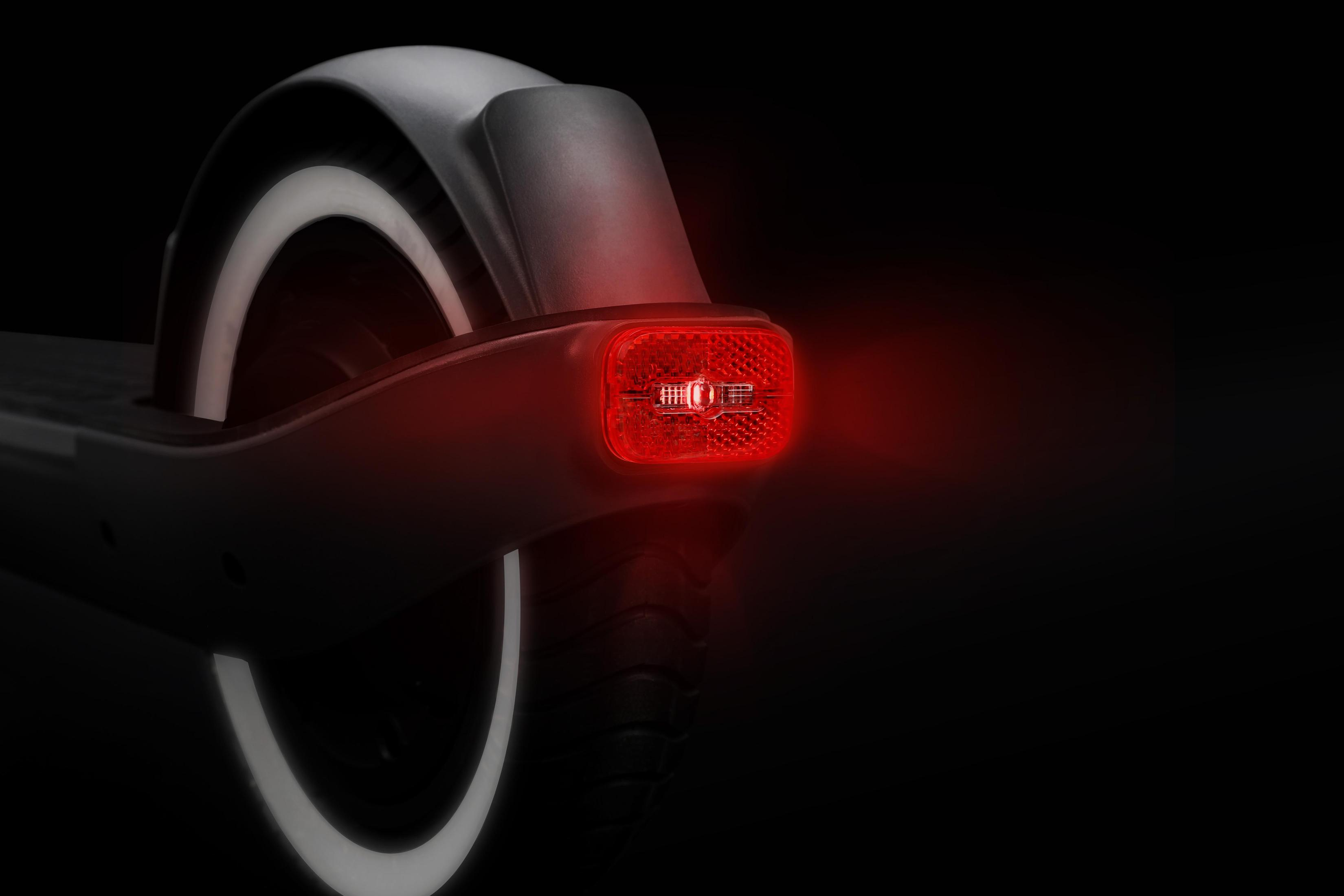 Nahaufnahme des Hecks eines Rollers, mit einem roten Licht. Der Hintergrund ist schwarz.
