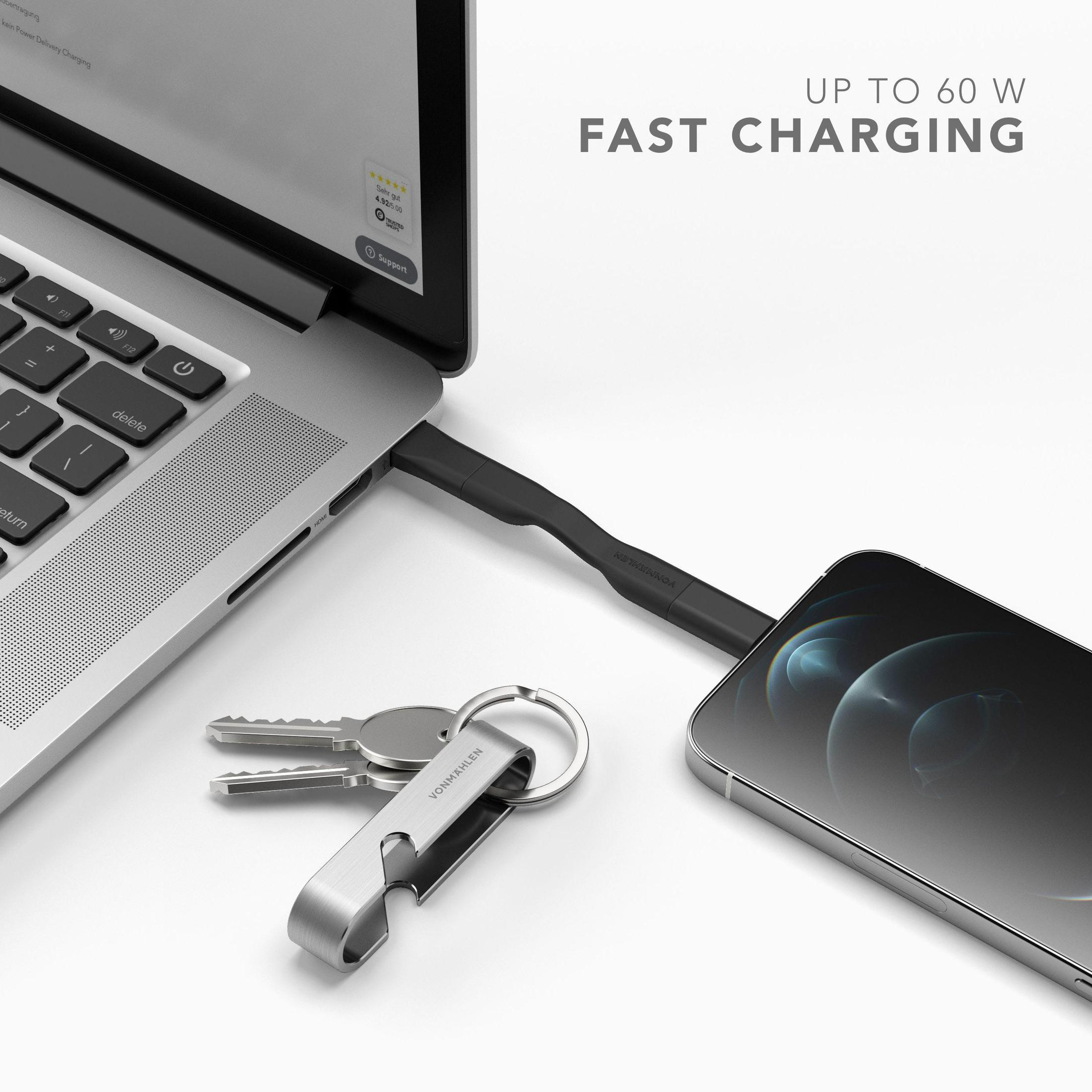 Laptop mit Ladekabel verbunden. Telefon und Schlüssel im Vordergrund, Text über Laden.