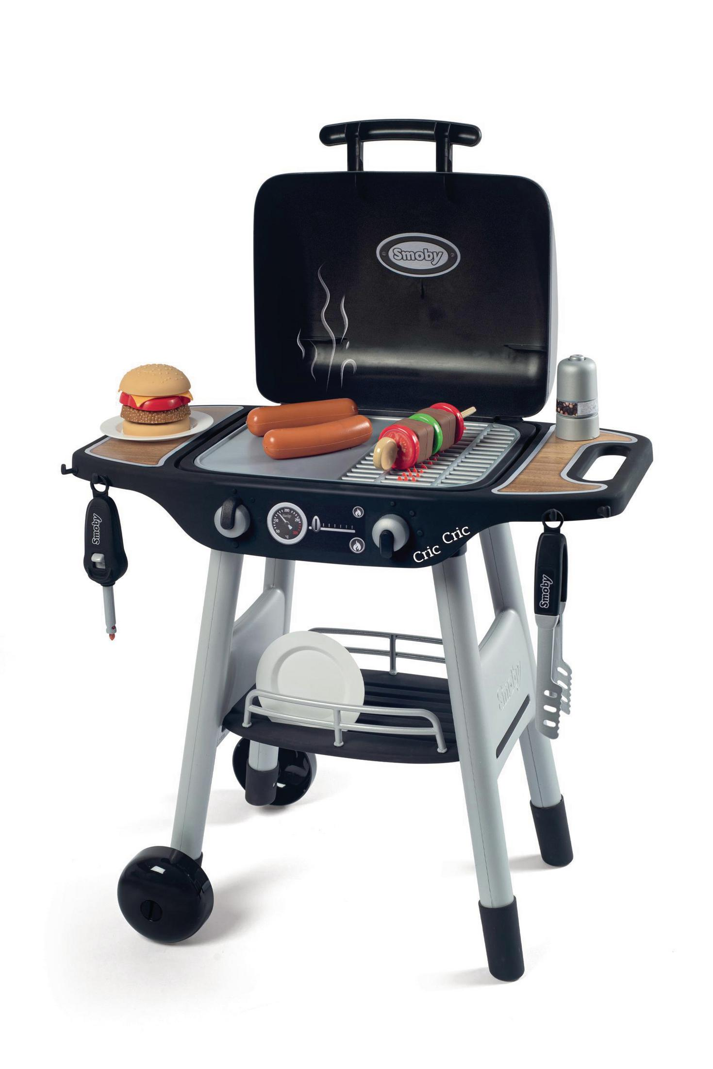 Spielzeuggrill mit Essen auf dem Grill. Ein Burger, Würstchen und Spieße. Der Grill ist schwarz und grau.