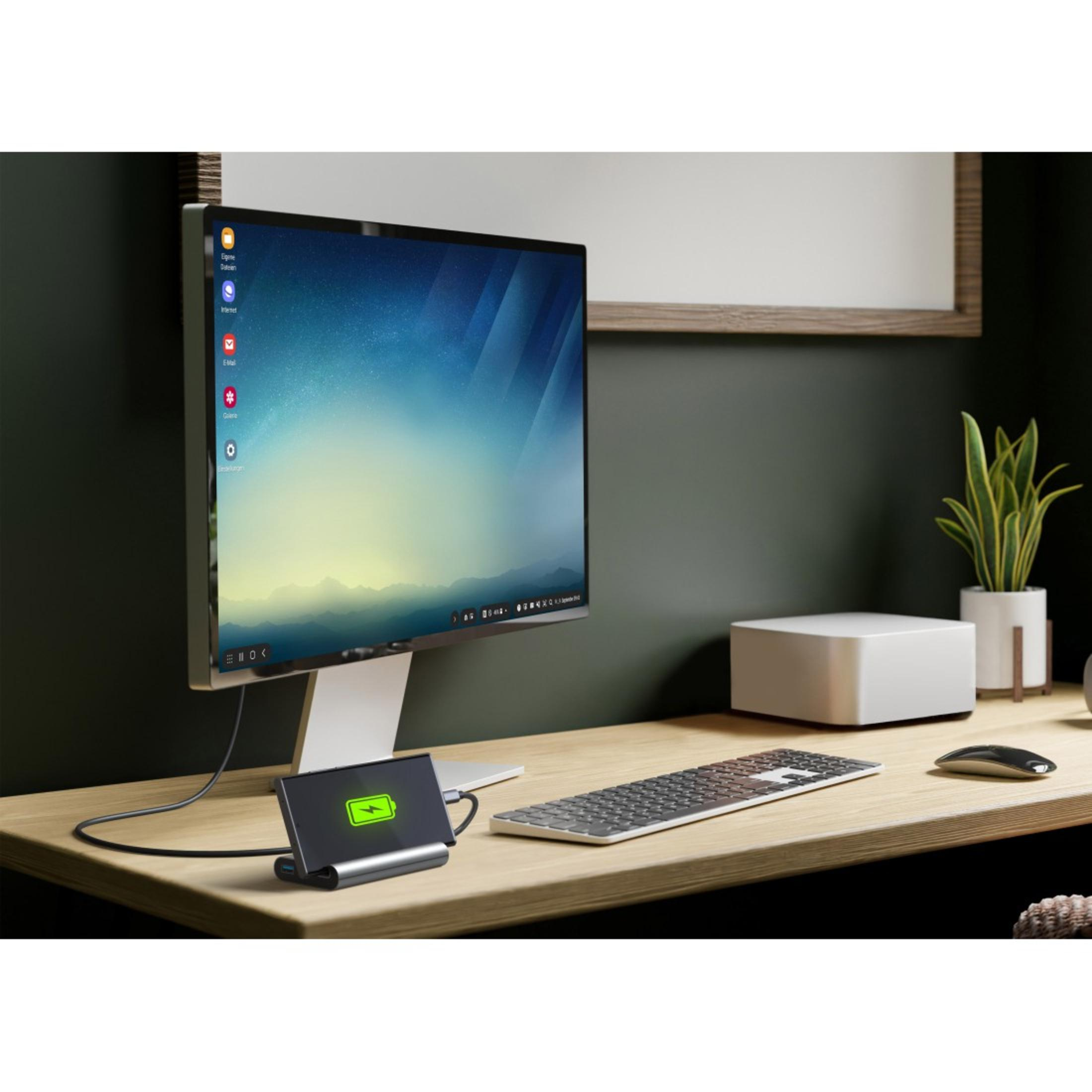 Ein Computer-Setup mit Monitor, Tastatur, Ladestation und einem weißen Computergehäuse.