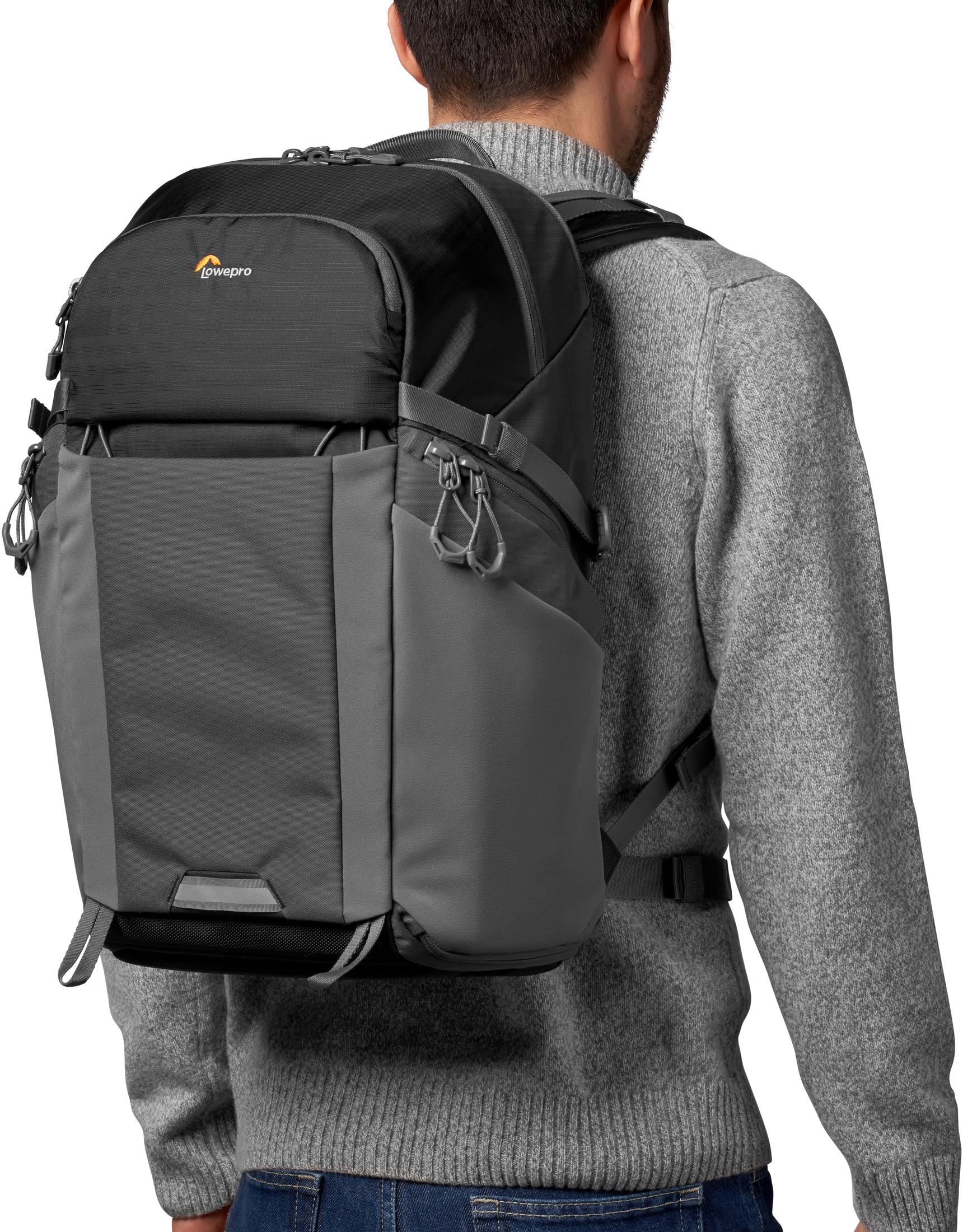 Person im grauen Pullover trägt einen grau-schwarzen Lowepro Kamera-Rucksack.