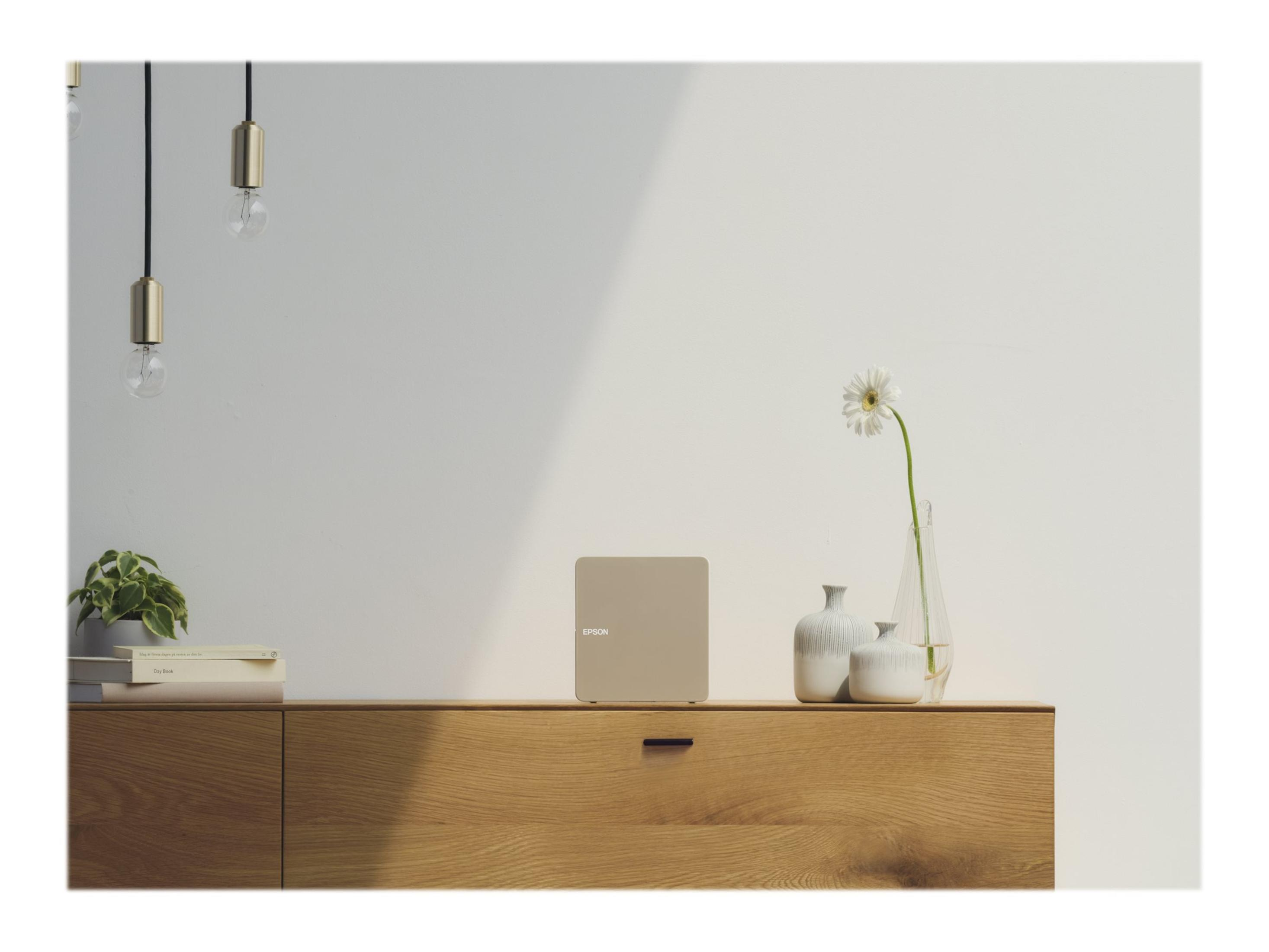 Ein Gerät in neutraler Farbe und einige Vasen auf einem Holzschrank vor einer weißen Wand.