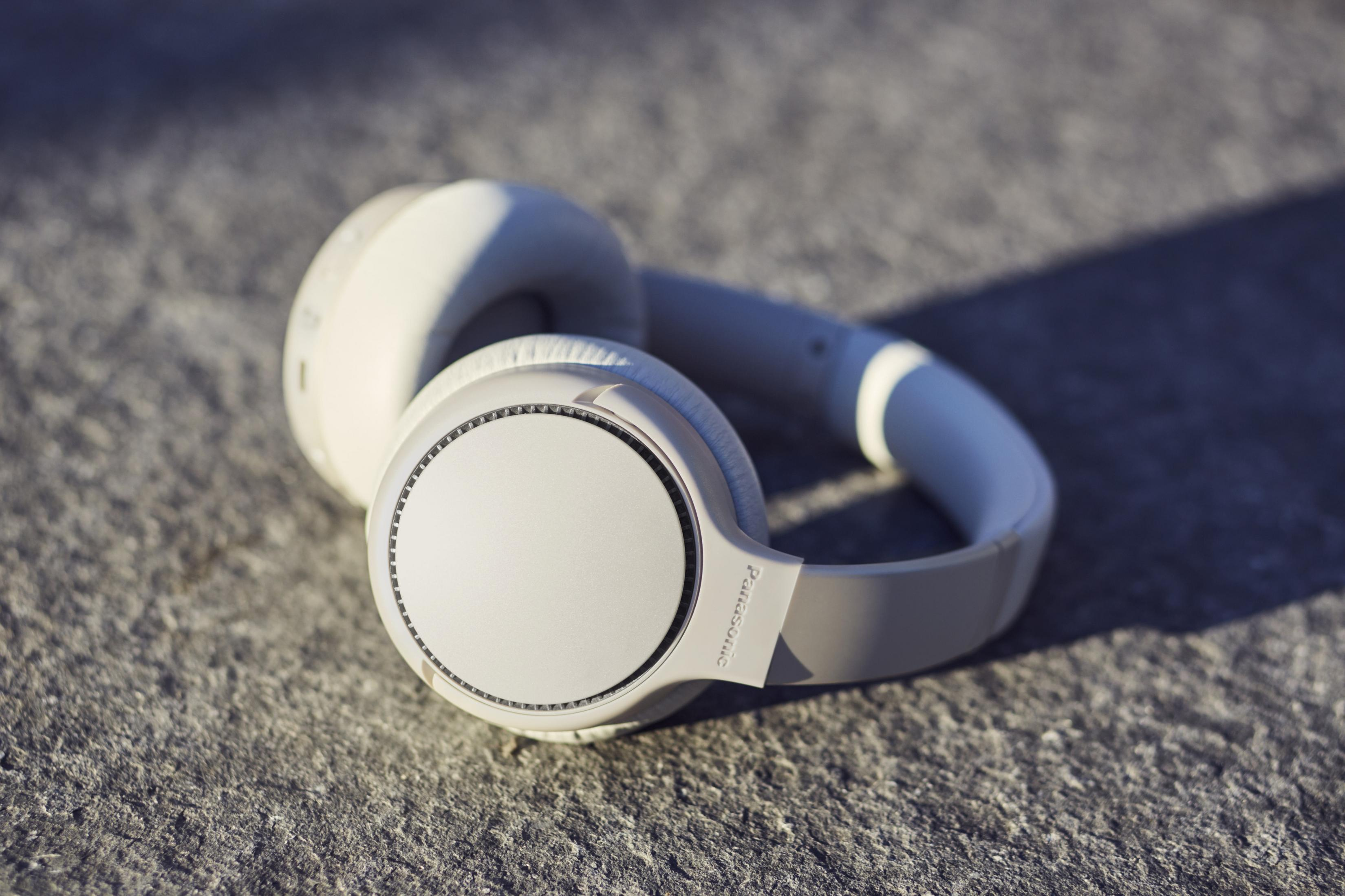 Auriculares blancos sobre una superficie de piedra gris. Los auriculares están orientados hacia arriba, mostrando los auriculares.