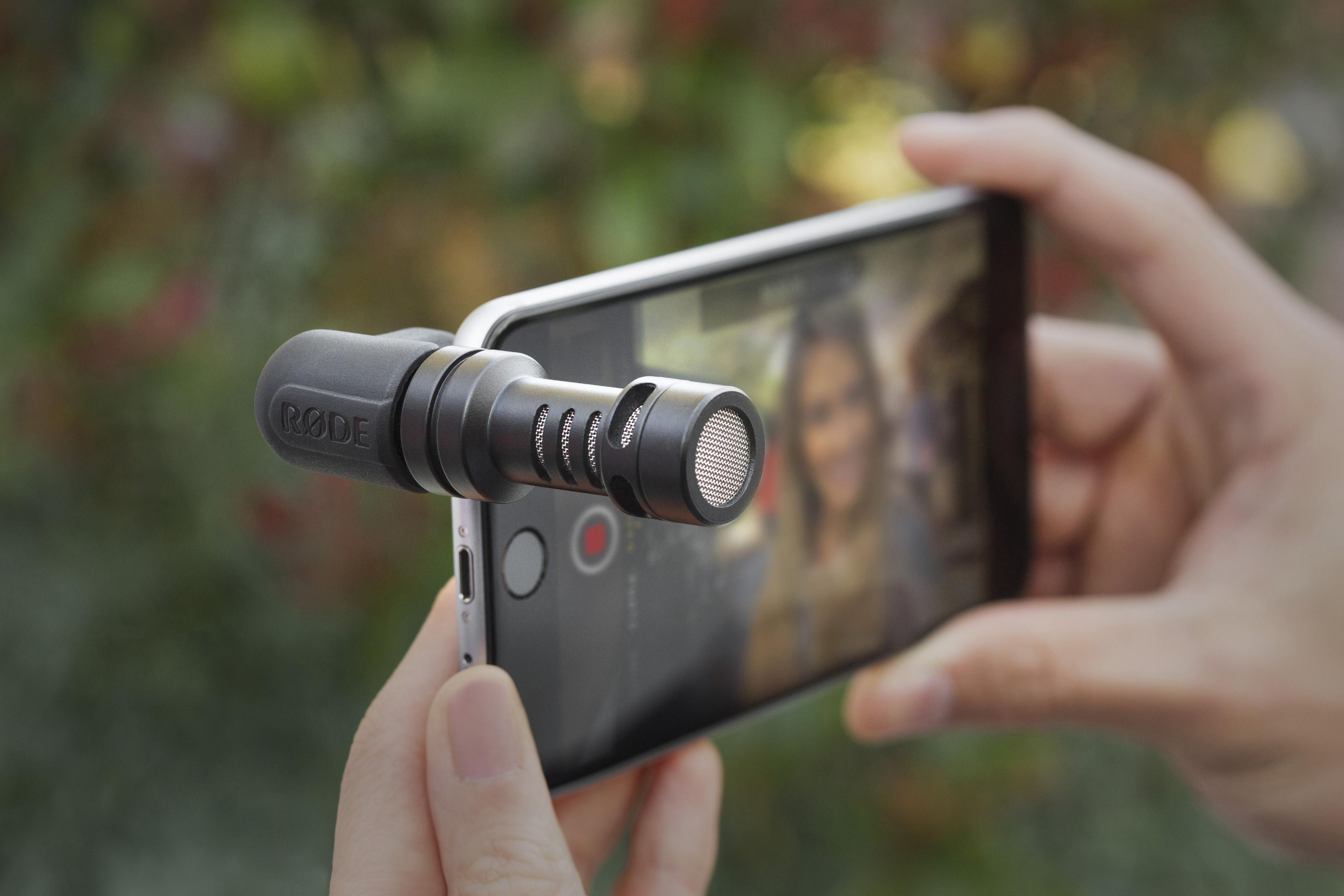 Eine Person hält ein Telefon mit Mikrofon, das ein Video aufnimmt.