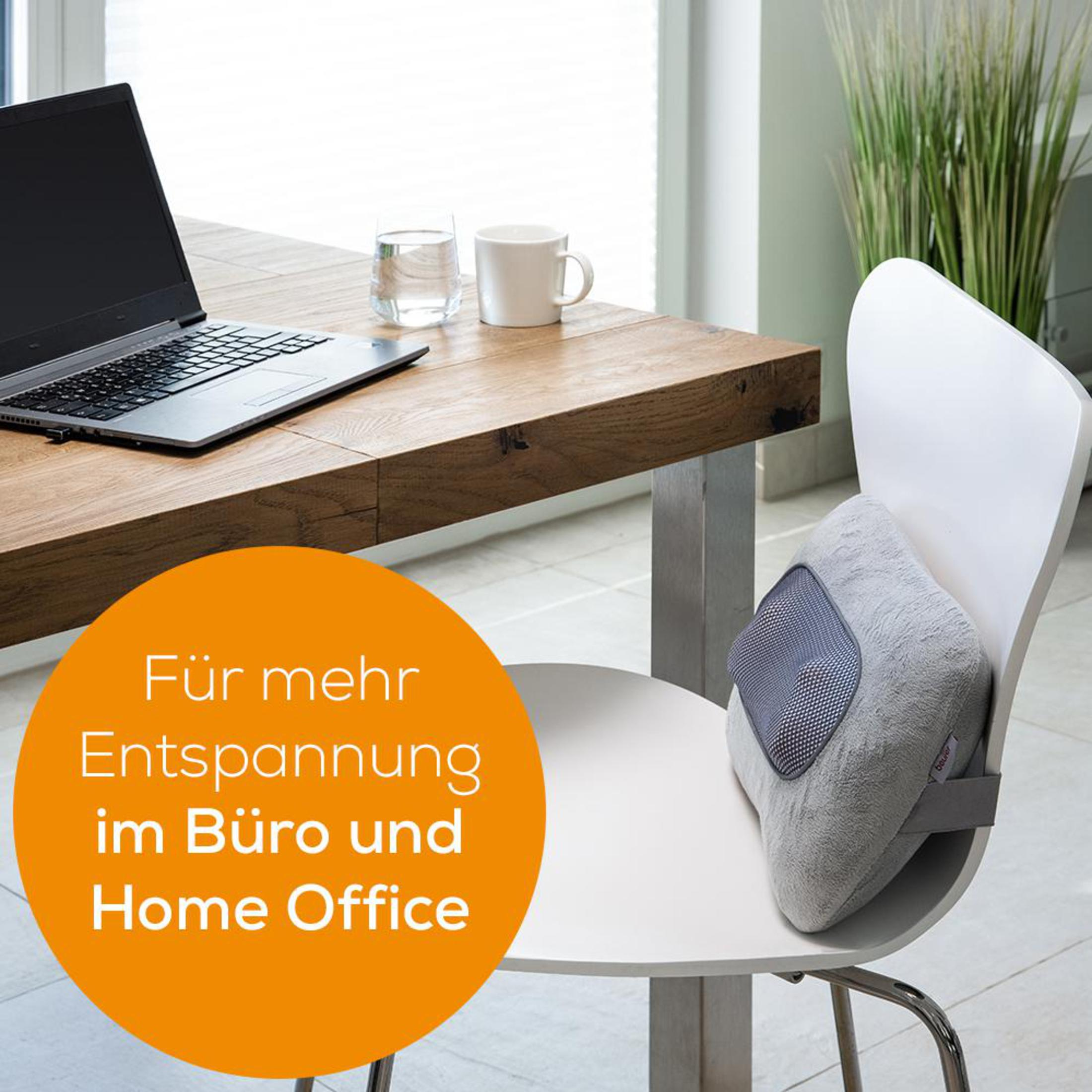 Scena d'ufficio con un laptop, una tazza e un cuscino di supporto lombare grigio su una sedia.