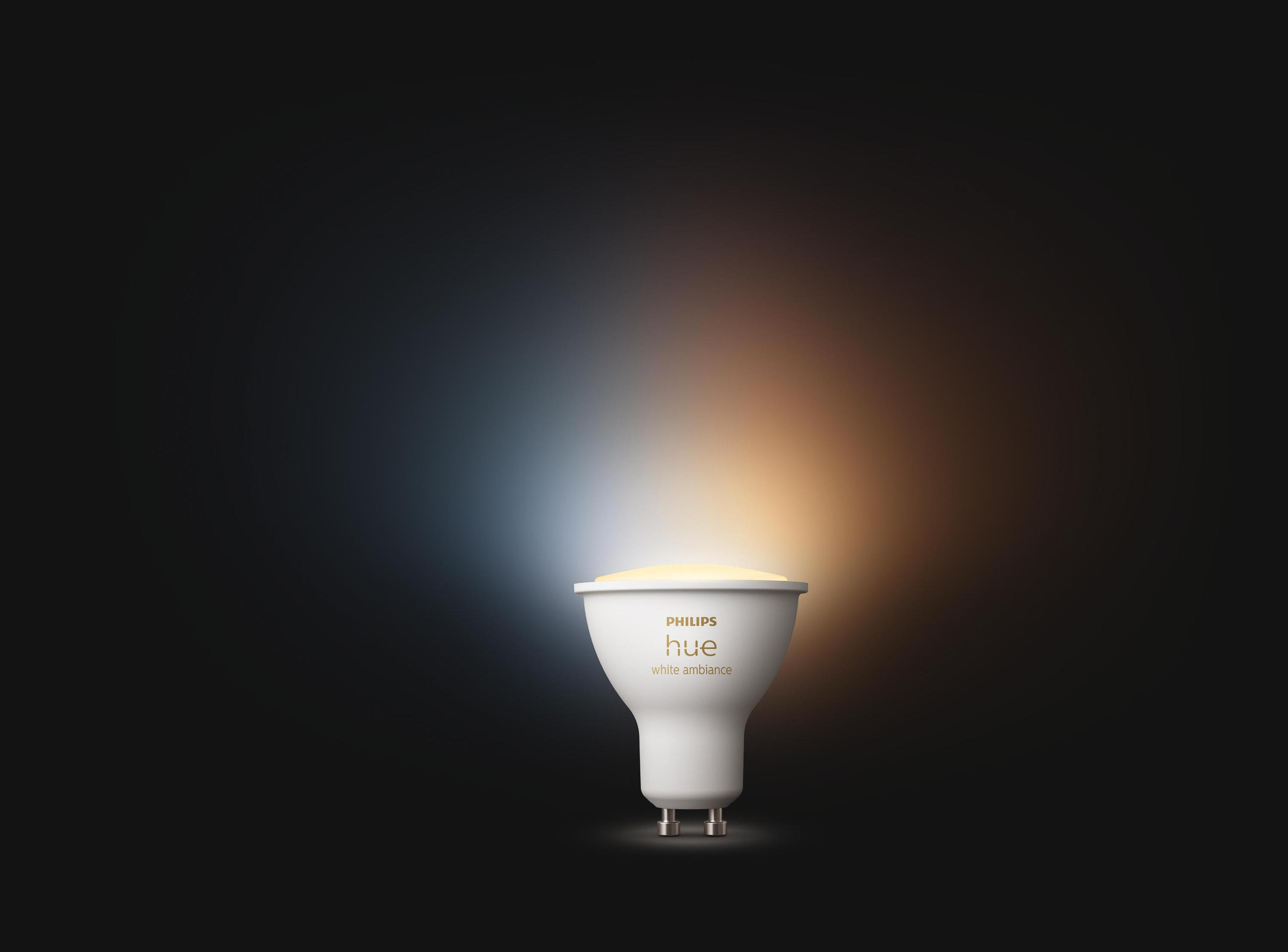 Weiße Philips Hue White Ambiance Glühbirne, die Licht ausstrahlt, auf dunklem Hintergrund.