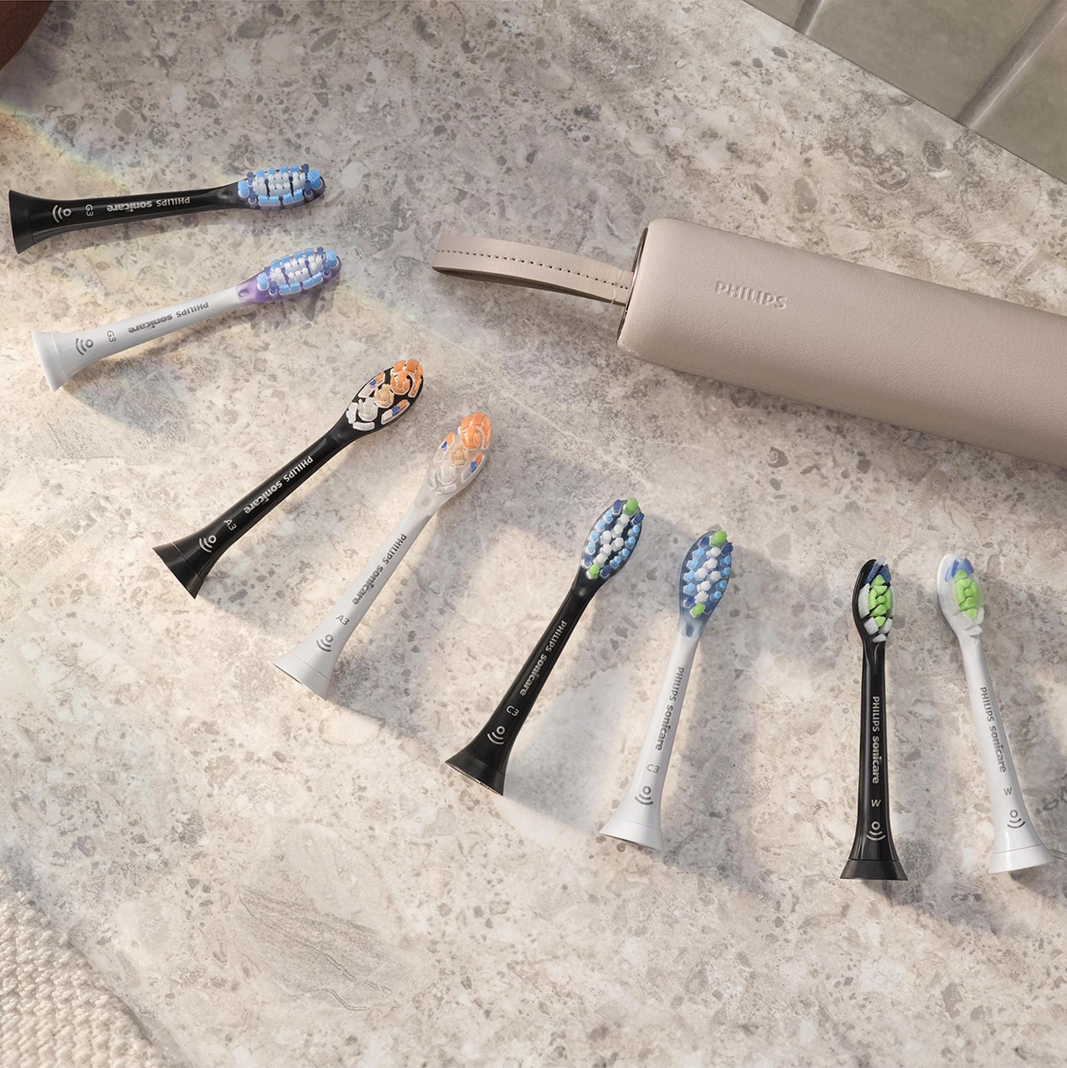 Wiele główek szczoteczek do zębów Philips Sonicare ułożonych na powierzchni z etui.