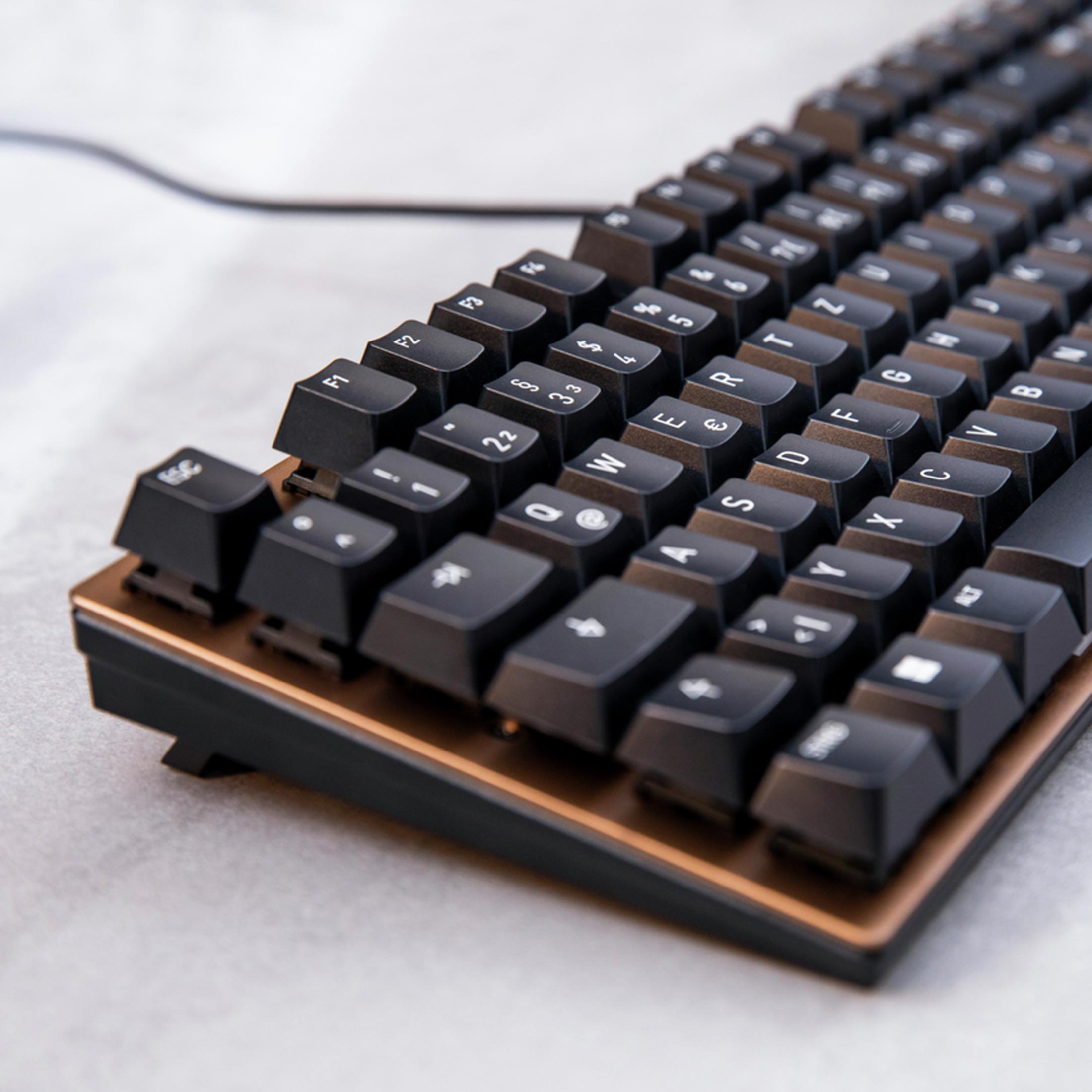 Nahaufnahme einer schwarzen mechanischen Tastatur mit Kupferakzenten, schräge Ansicht.