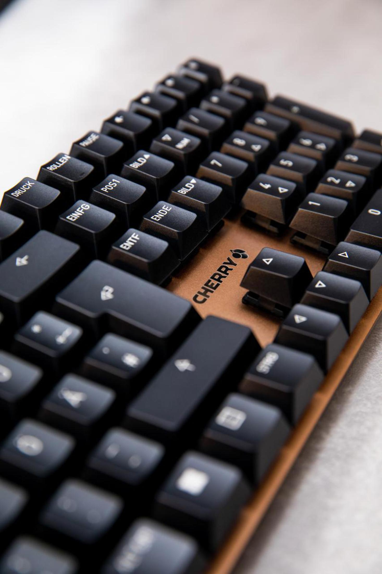 Nahaufnahme einer schwarzen Tastatur mit schwarzen Tasten. Das Cherry-Logo ist auf der Leertaste sichtbar.