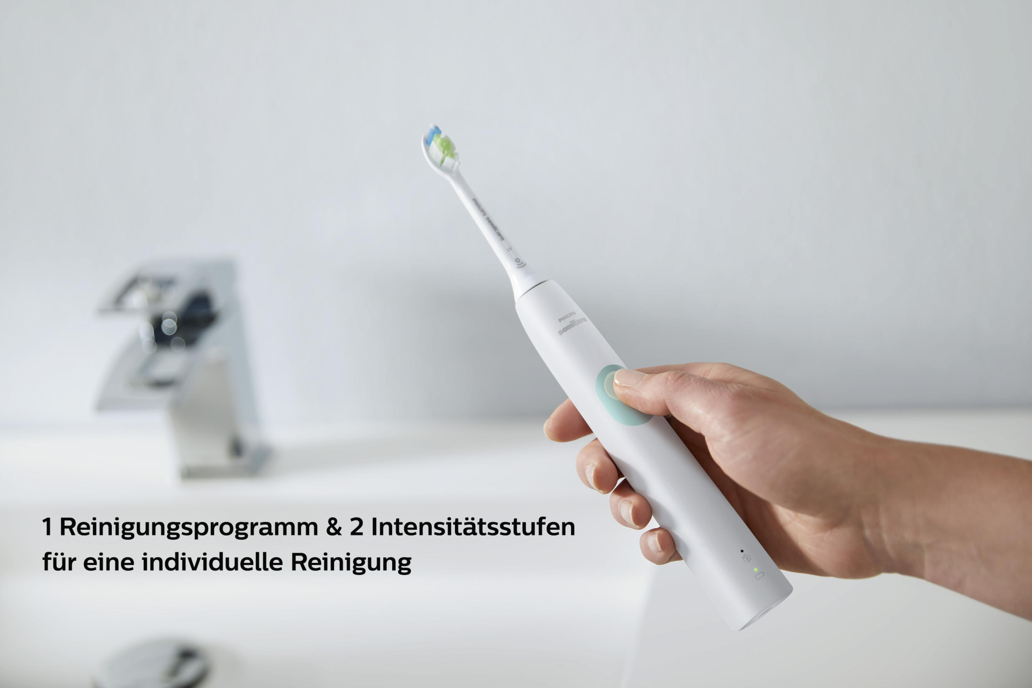 Spazzolino elettrico bianco tenuto in mano. Sopra un lavandino. Testo a sinistra.