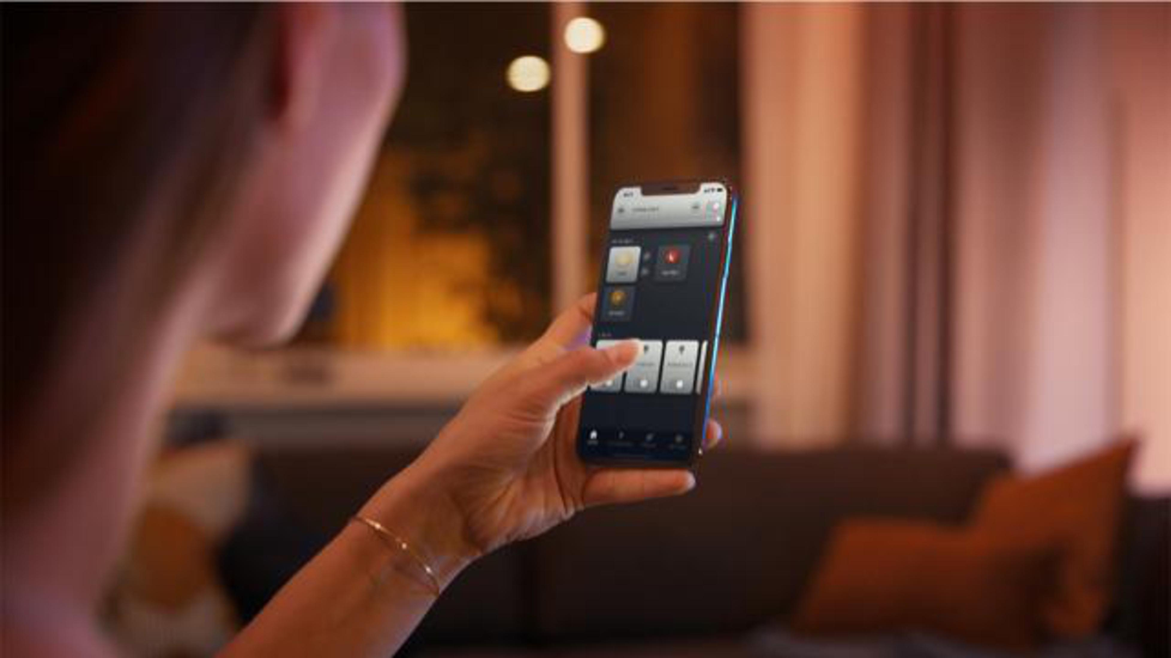 Dłoń osoby trzymająca smartfon. Telefon wyświetla interfejs aplikacji z ikonami.