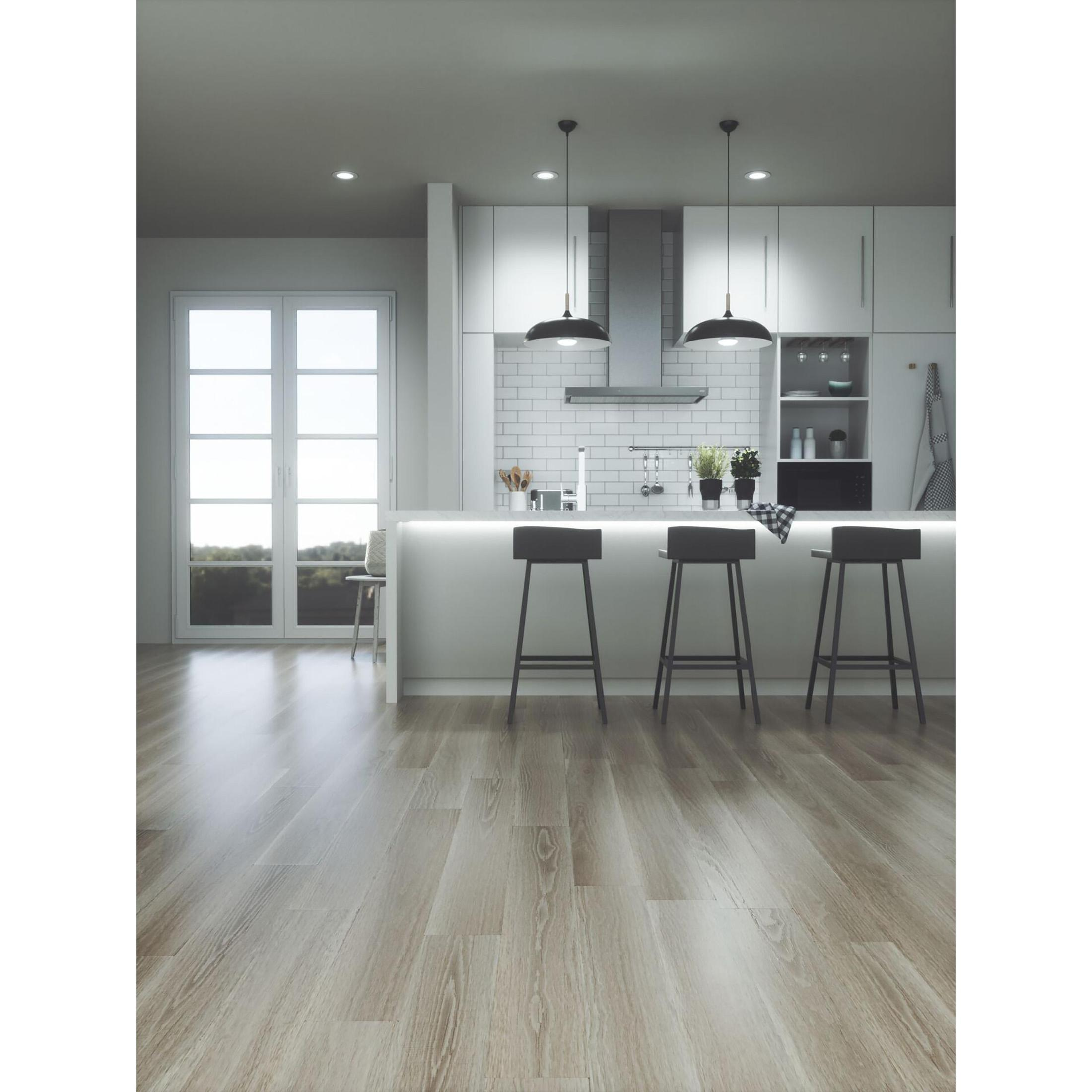 Cucina moderna con sgabelli da bar, pavimenti in legno e illuminazione brillante.
