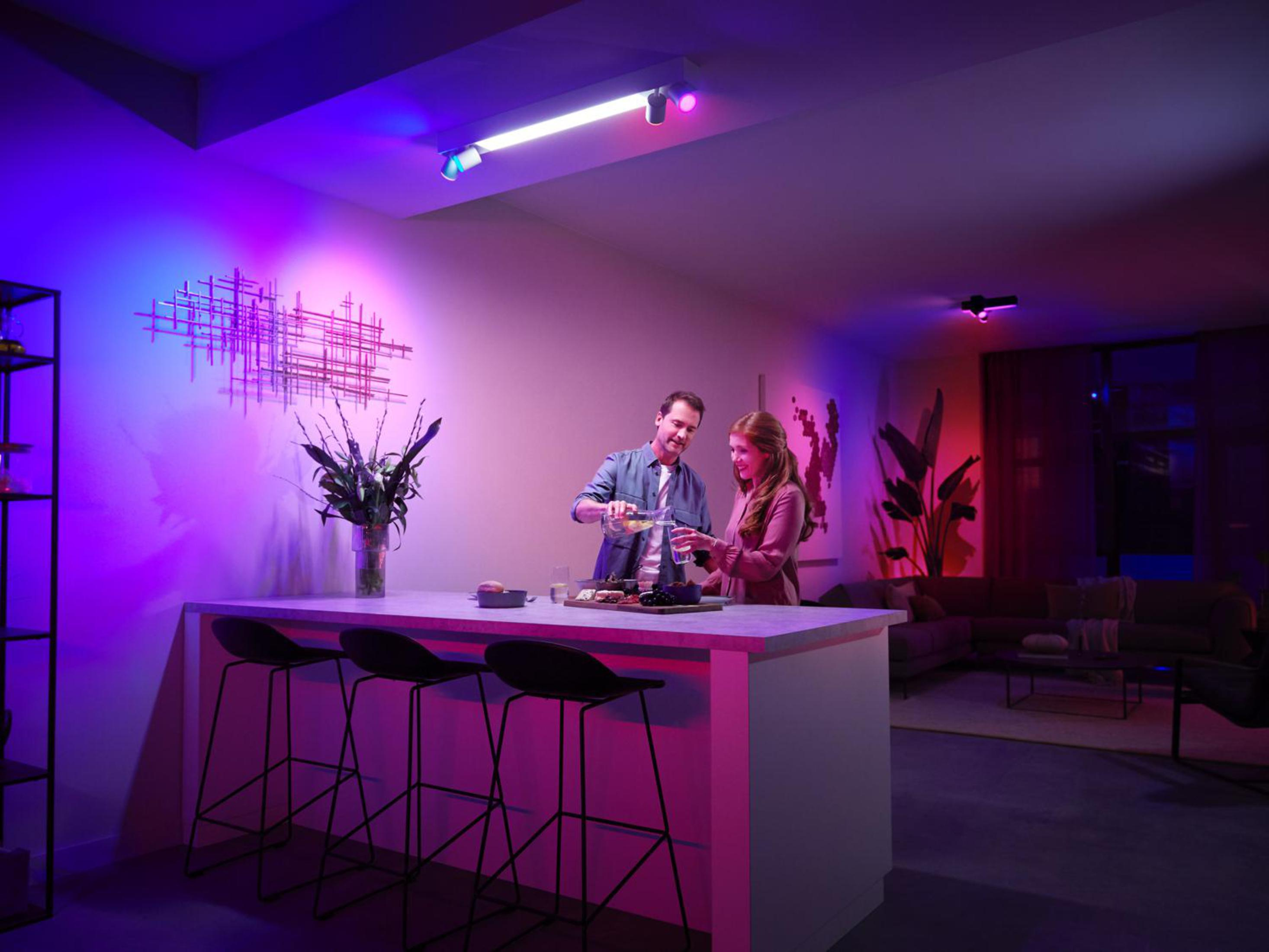 Una coppia versa vino in una stanza con luci colorate, un bar e un'opera d'arte moderna.