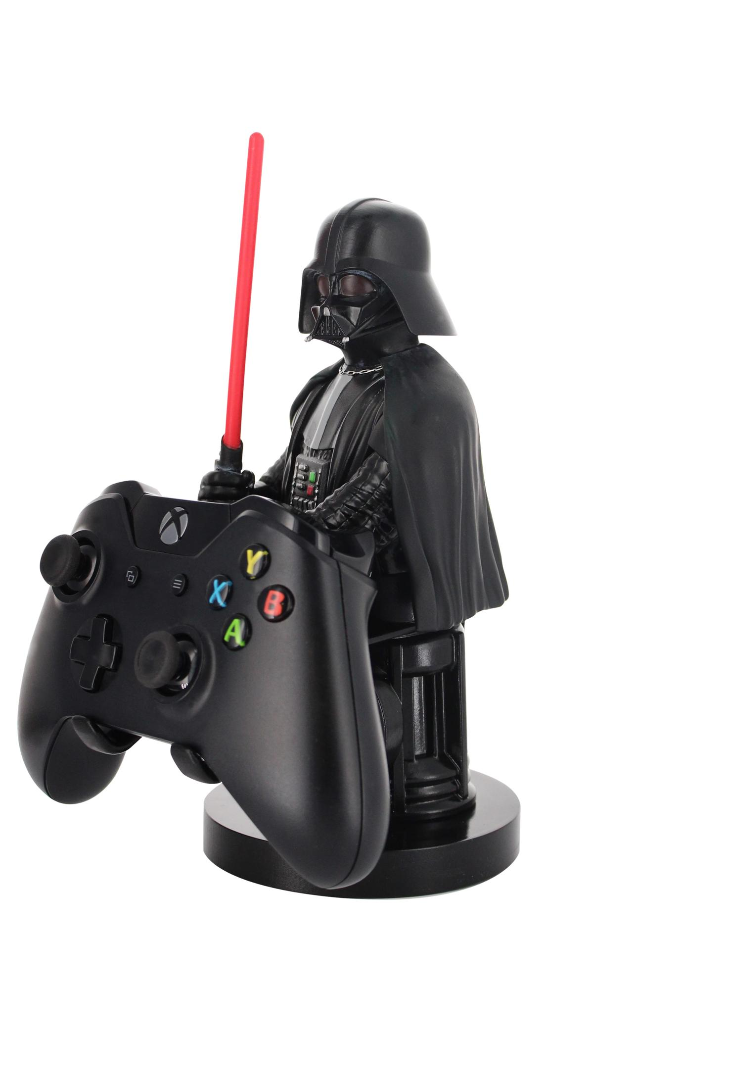 Una statuetta di Darth Vader tiene un controller Xbox nero. Ha una spada laser rossa. Sfondo bianco.