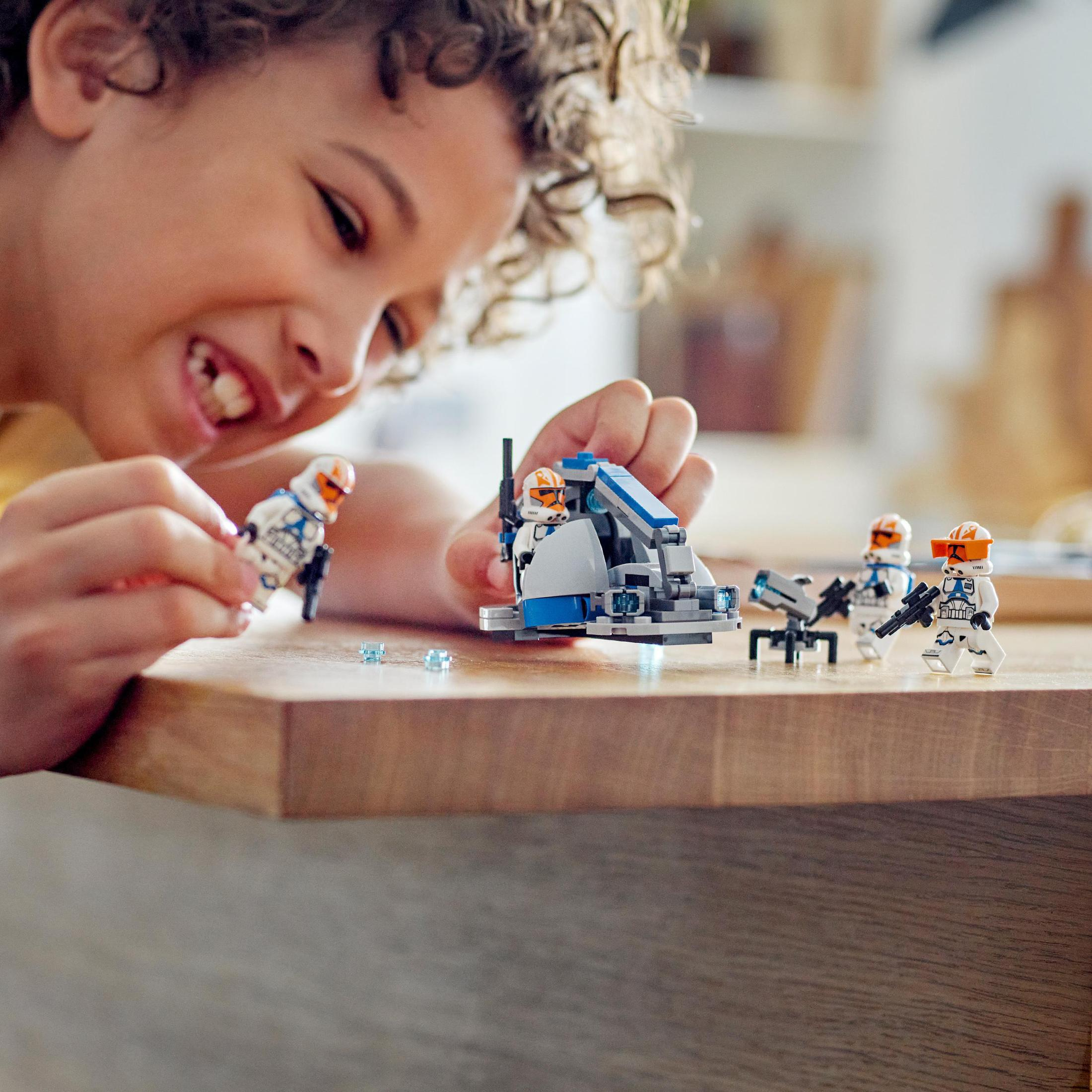 Een jongen speelt met Lego-figuren en een speelgoedvoertuig in een kamer.
