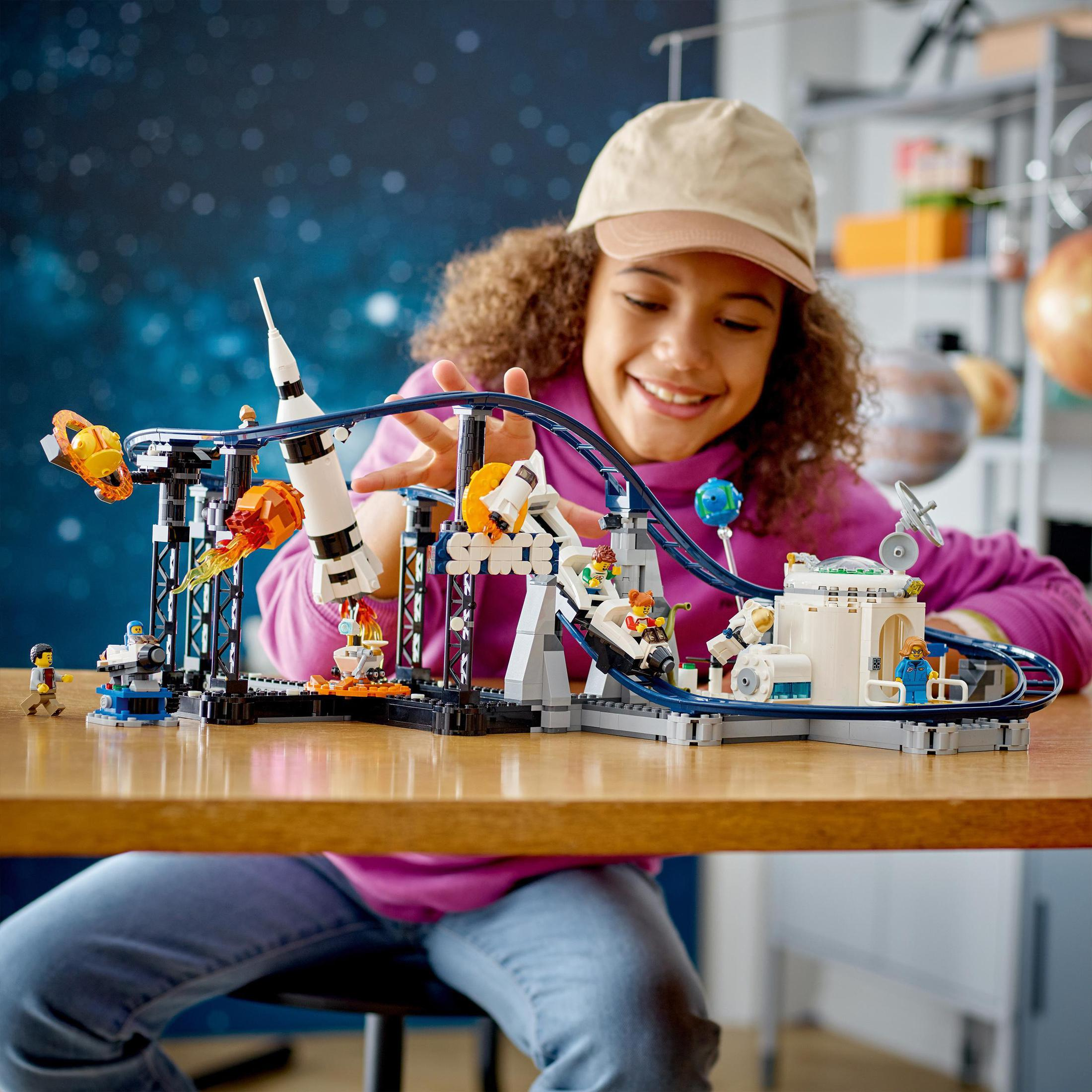 Bir kız, uzay temalı bir Lego hız treniyle oynuyor. Sahne renkli ve iç mekanda.