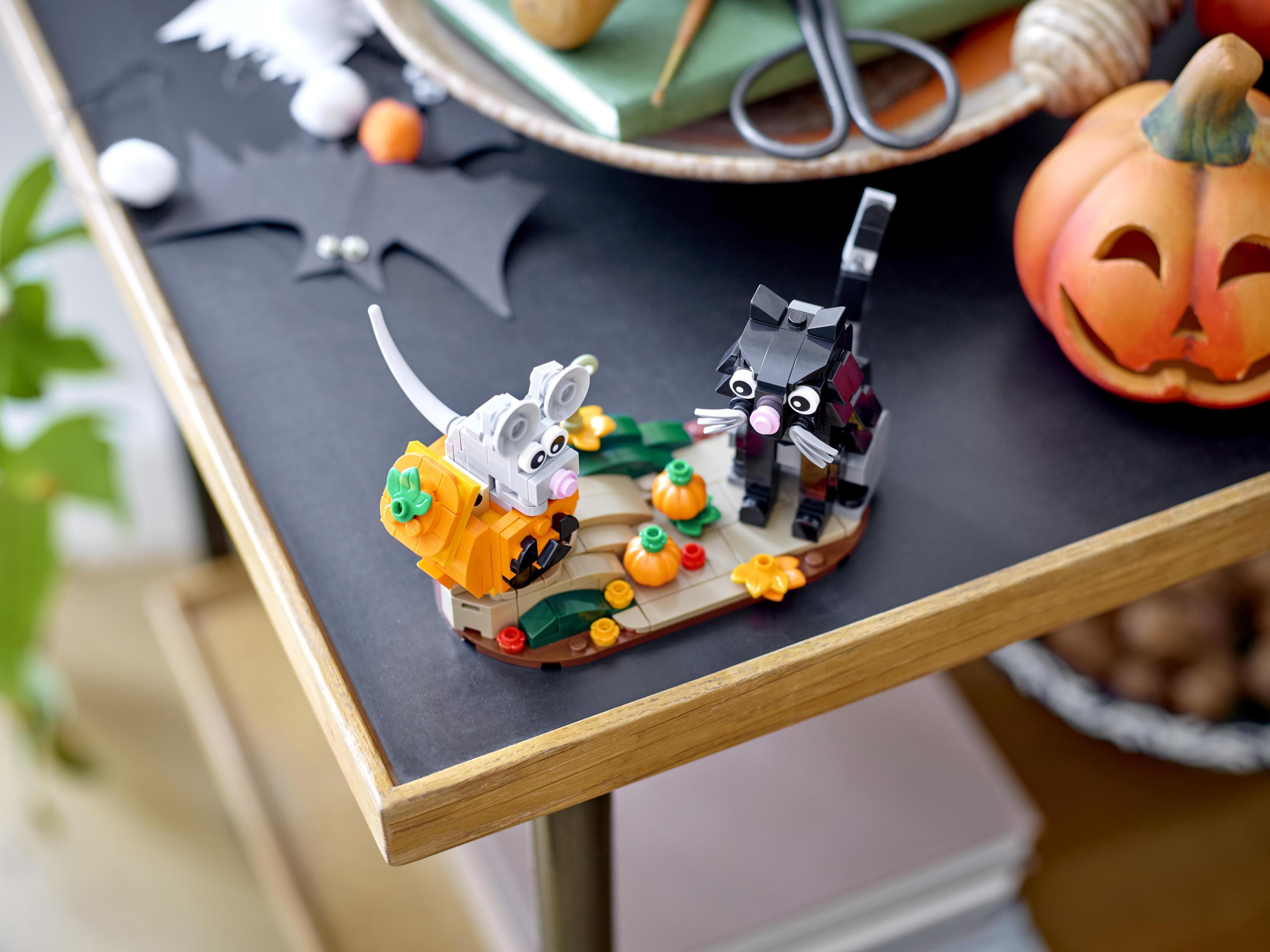 Scena z klocków Lego z kotem, myszą i dyniami na stole. Motyw Halloween.