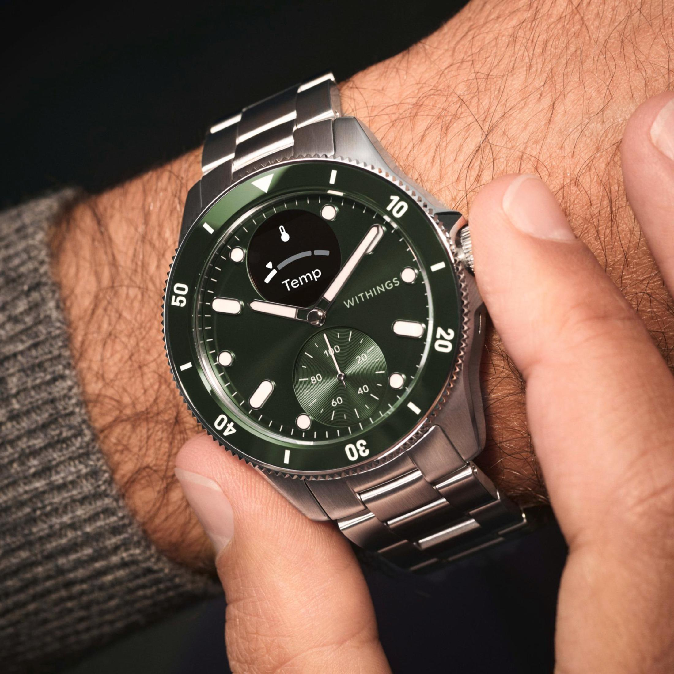 Silberne Smartwatch mit grünem Zifferblatt. Die Uhr zeigt eine Temperaturmessung an.