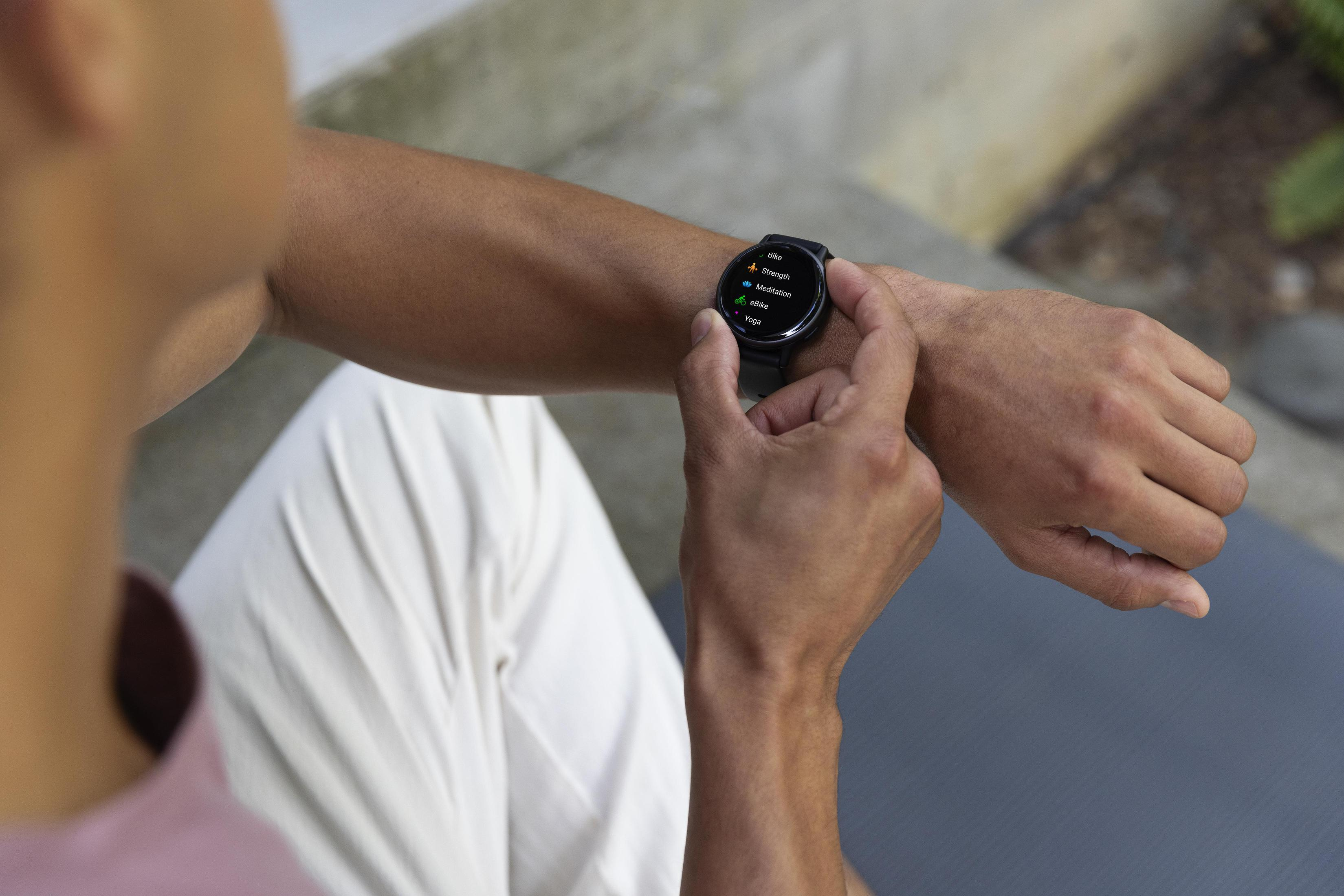 Mann schaut auf Smartwatch mit Trainingsoptionen auf dem Handgelenk.
