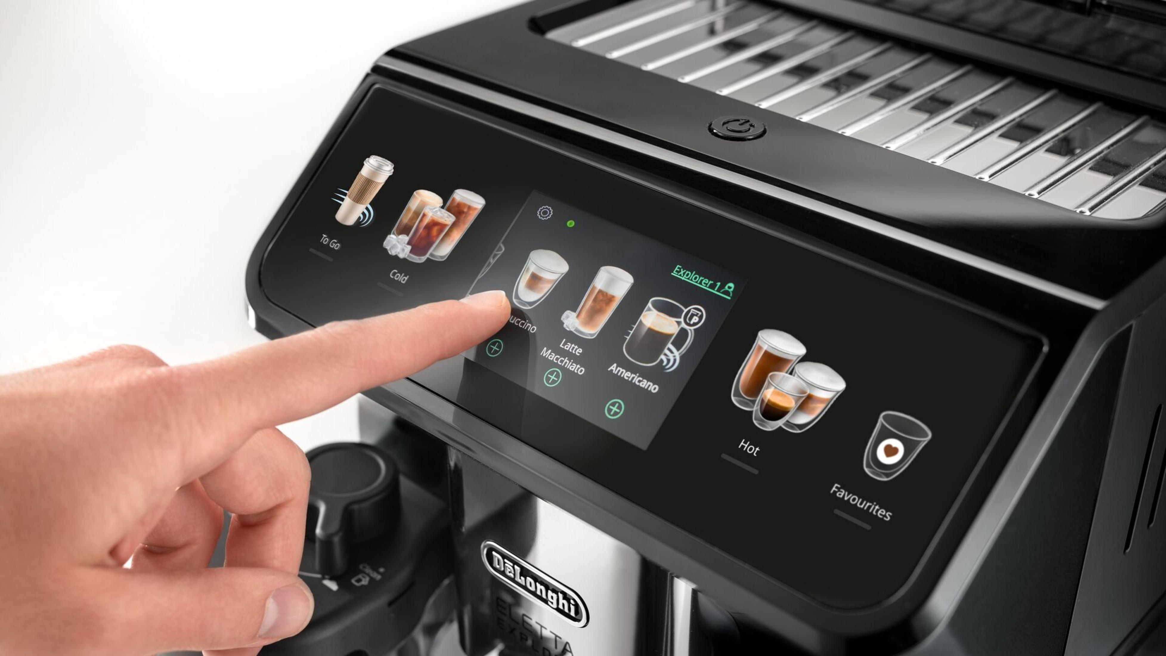 A hand touching a coffee machine touchscreen, with coffee type options, black and silver.