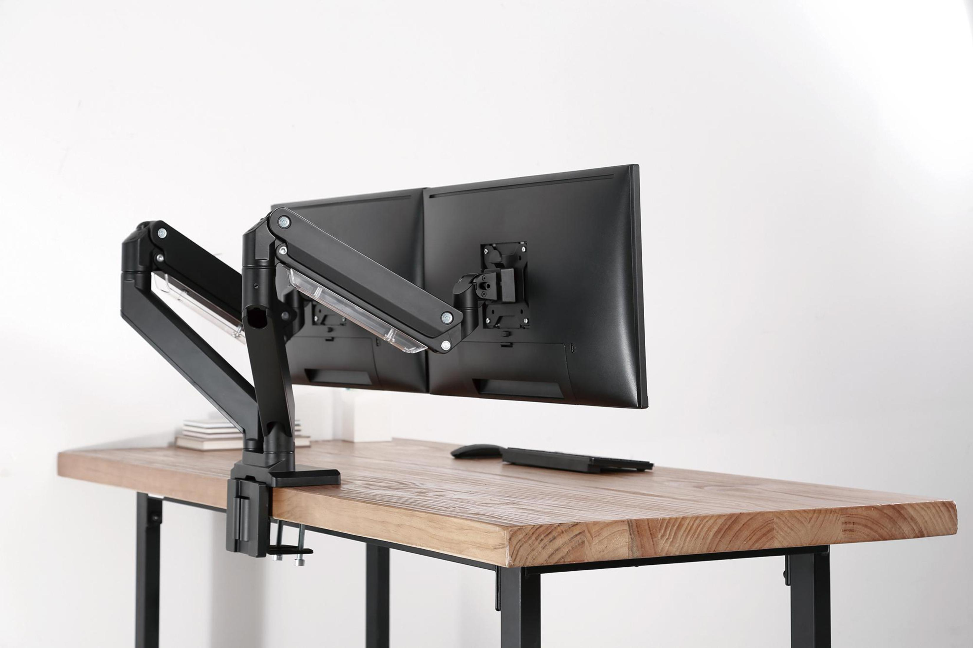 Monitor auf einem Holztisch mit schwarzem Arm. Maus und Fernbedienung liegen auch auf dem Tisch.